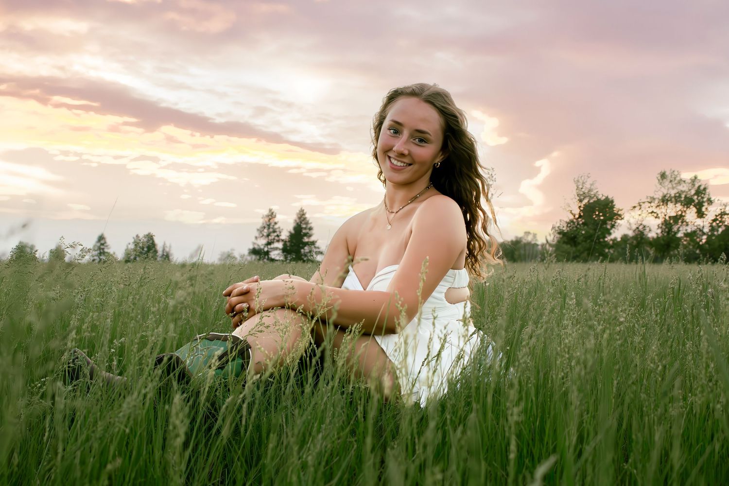 Young woman sitting in tall grass smiling