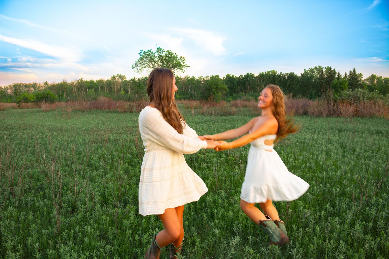 two female friends posing in a field at sunset