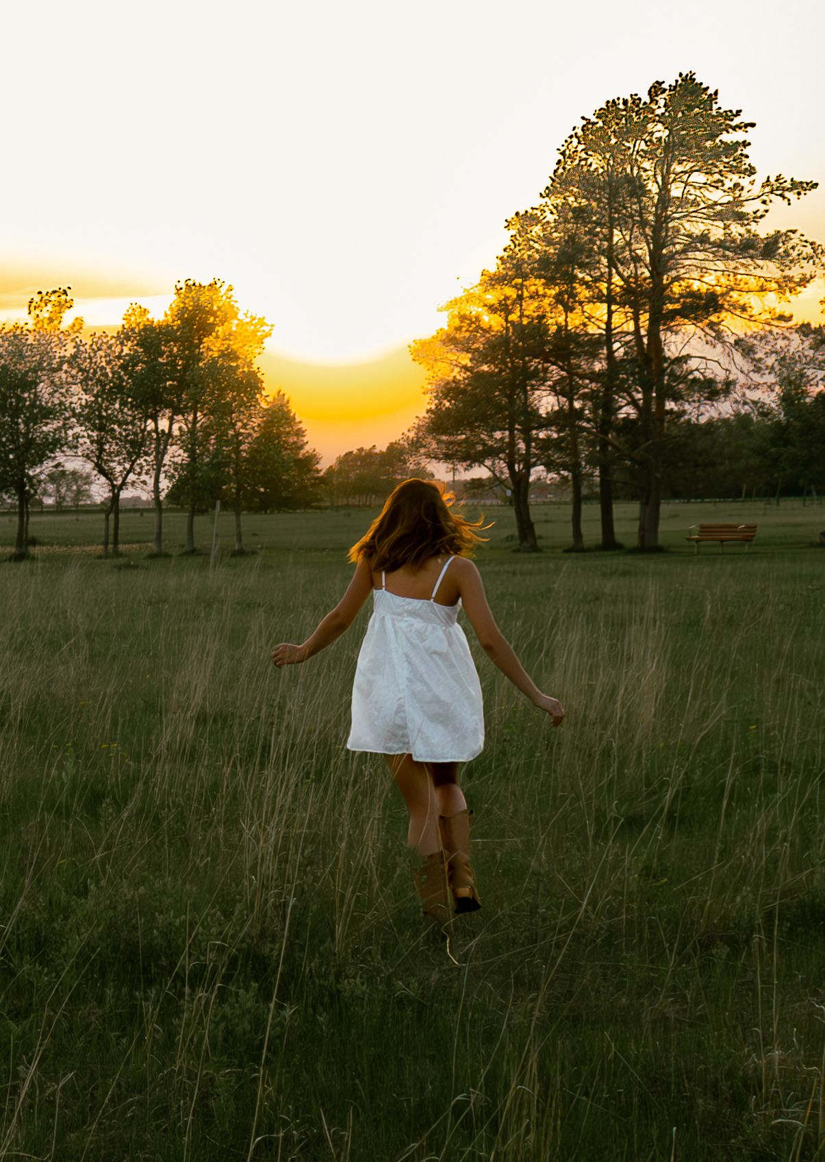 young woman posing in a field at sunset