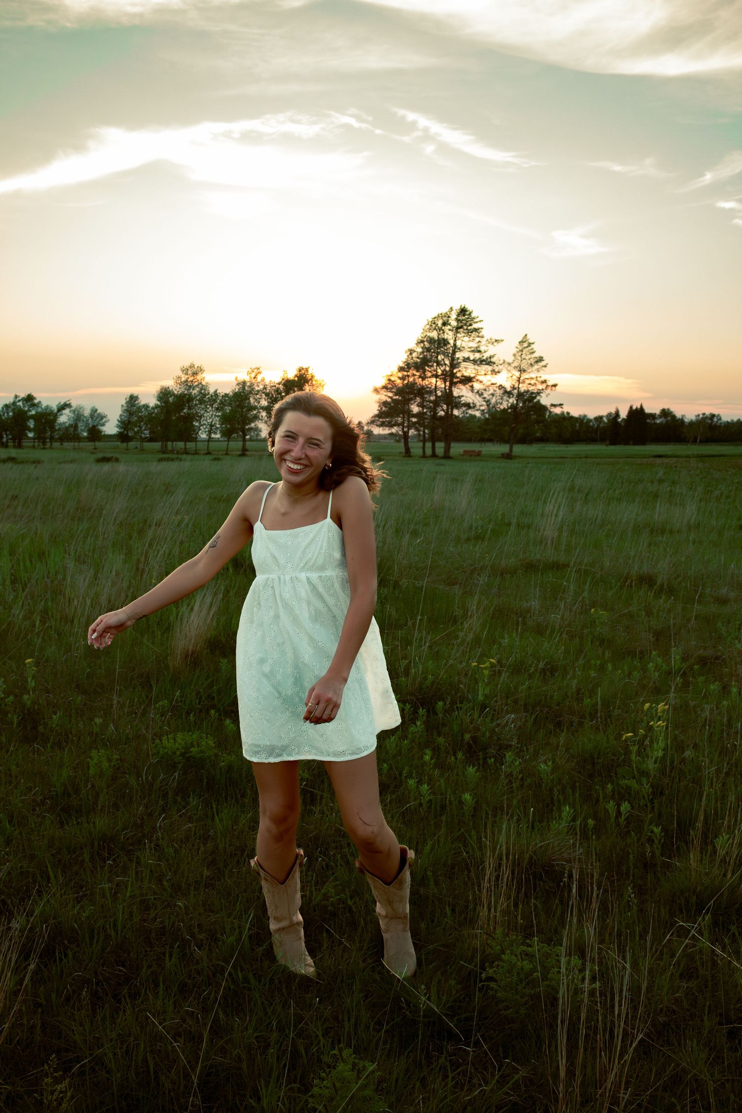 young woman posing in a field at sunset