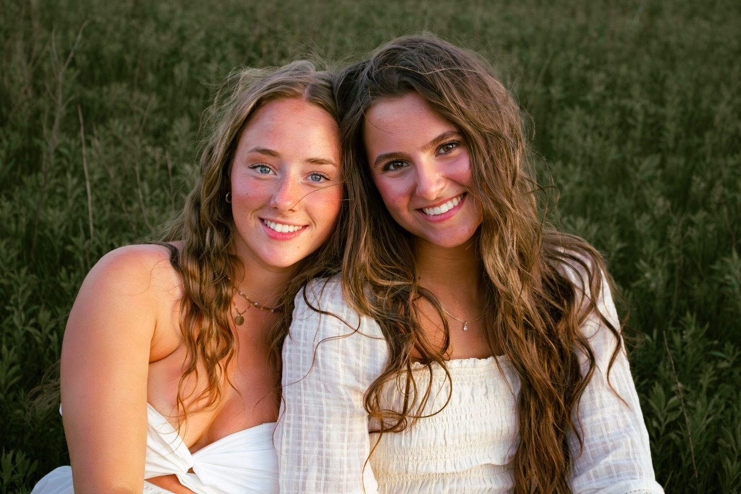 two female friends posing in a field at sunset