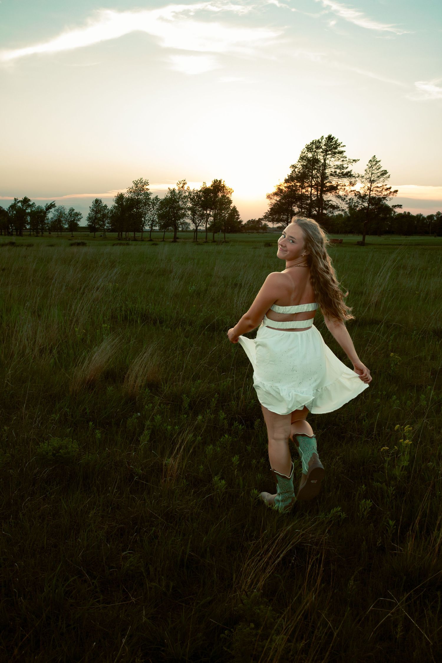 young woman posing in a field at sunset