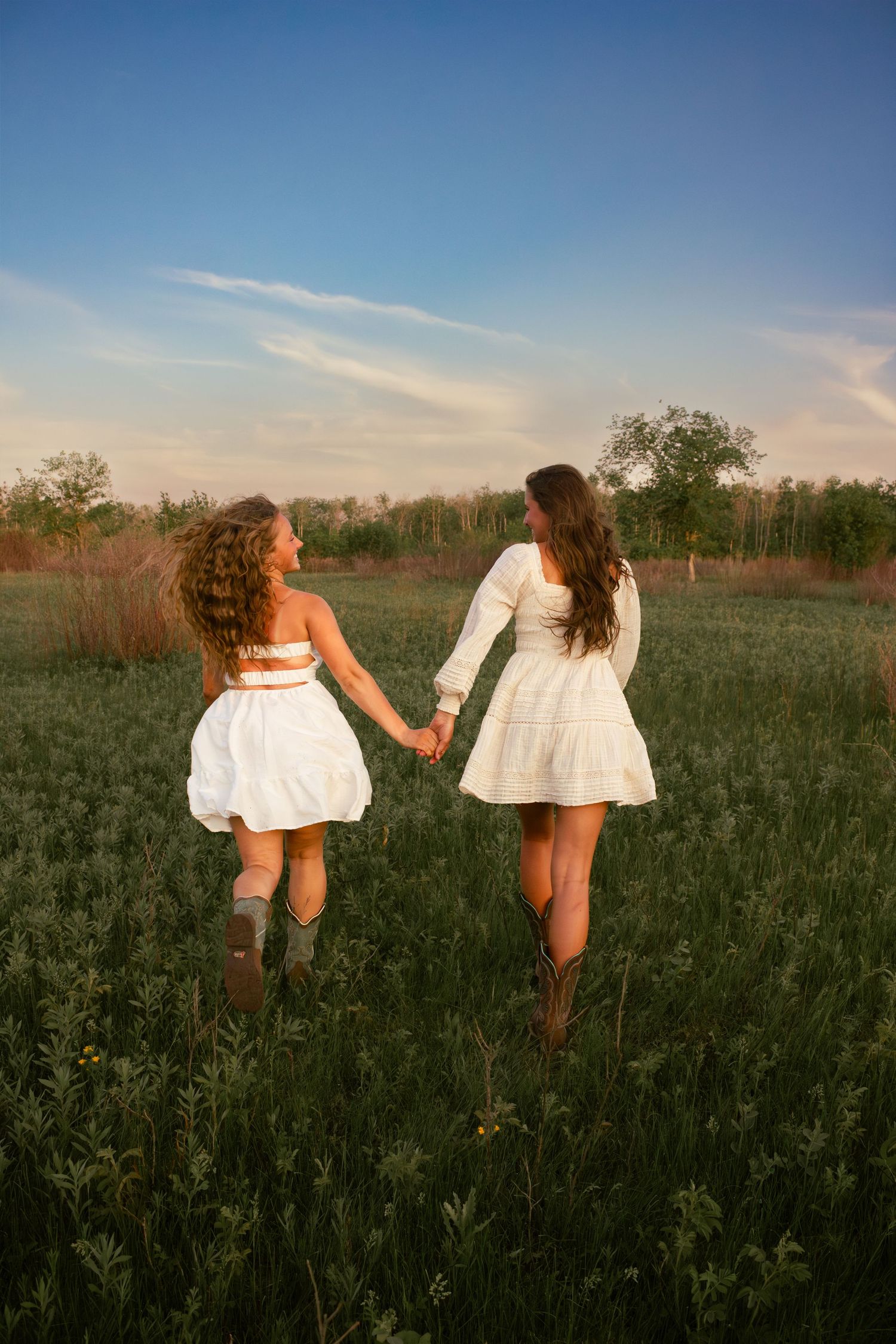 two female friends posing in a field at sunset