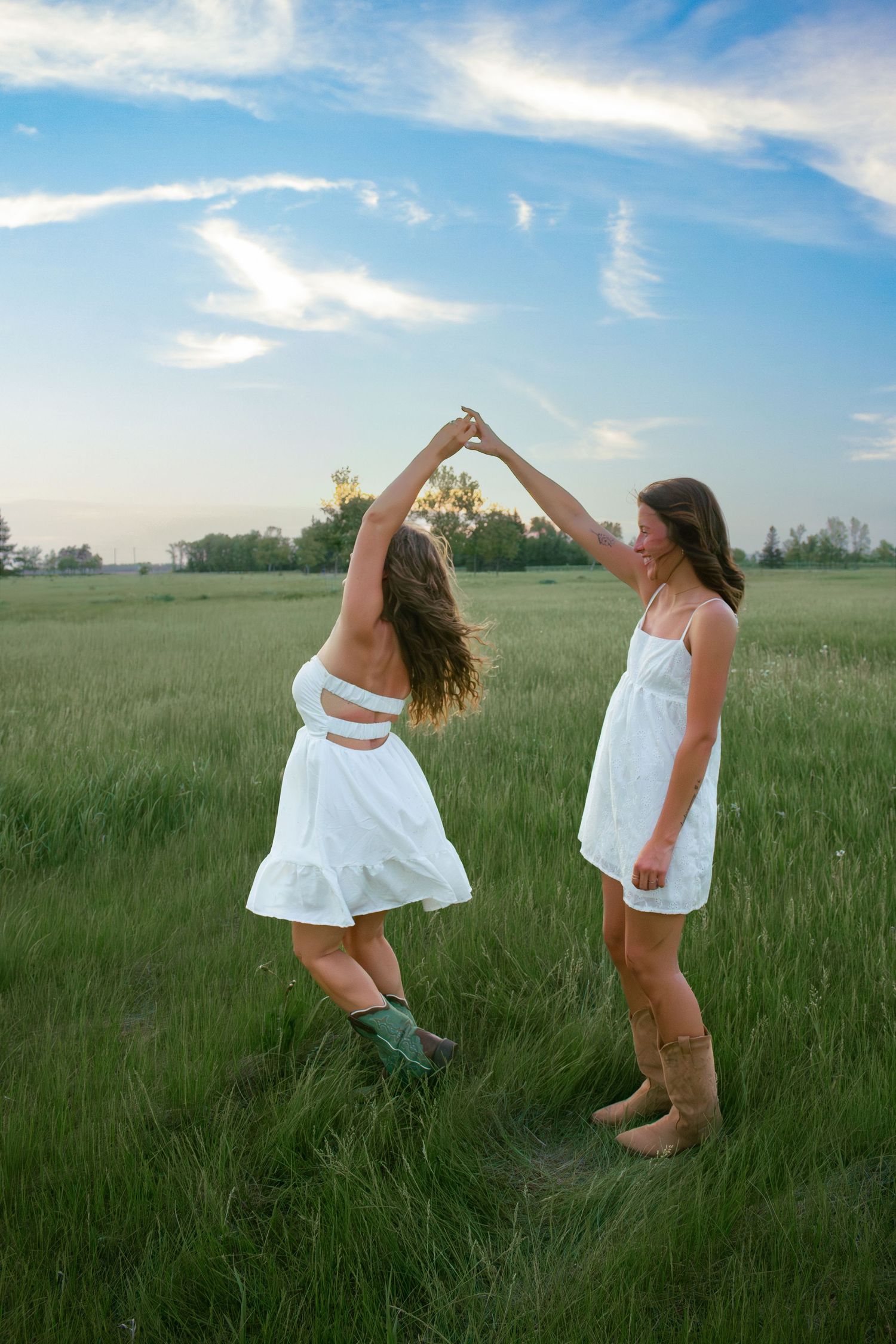 two female friends posing in a field at sunset