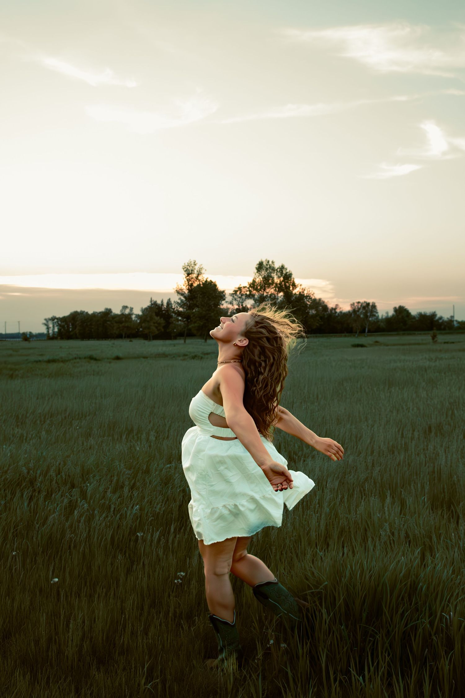 young woman posing in a field at sunset