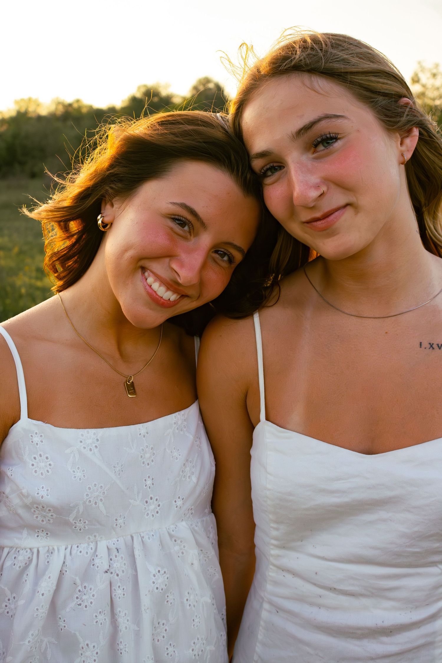 two female friends posing in a field at sunset