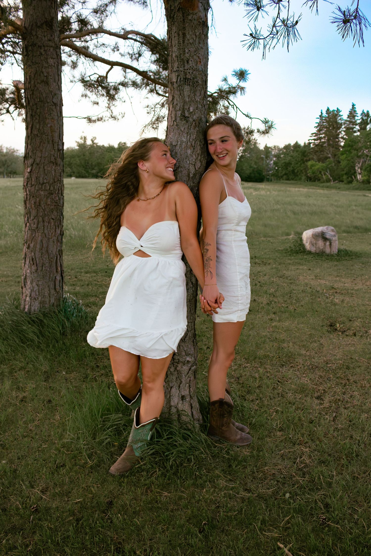 two female friends posing in a field at sunset
