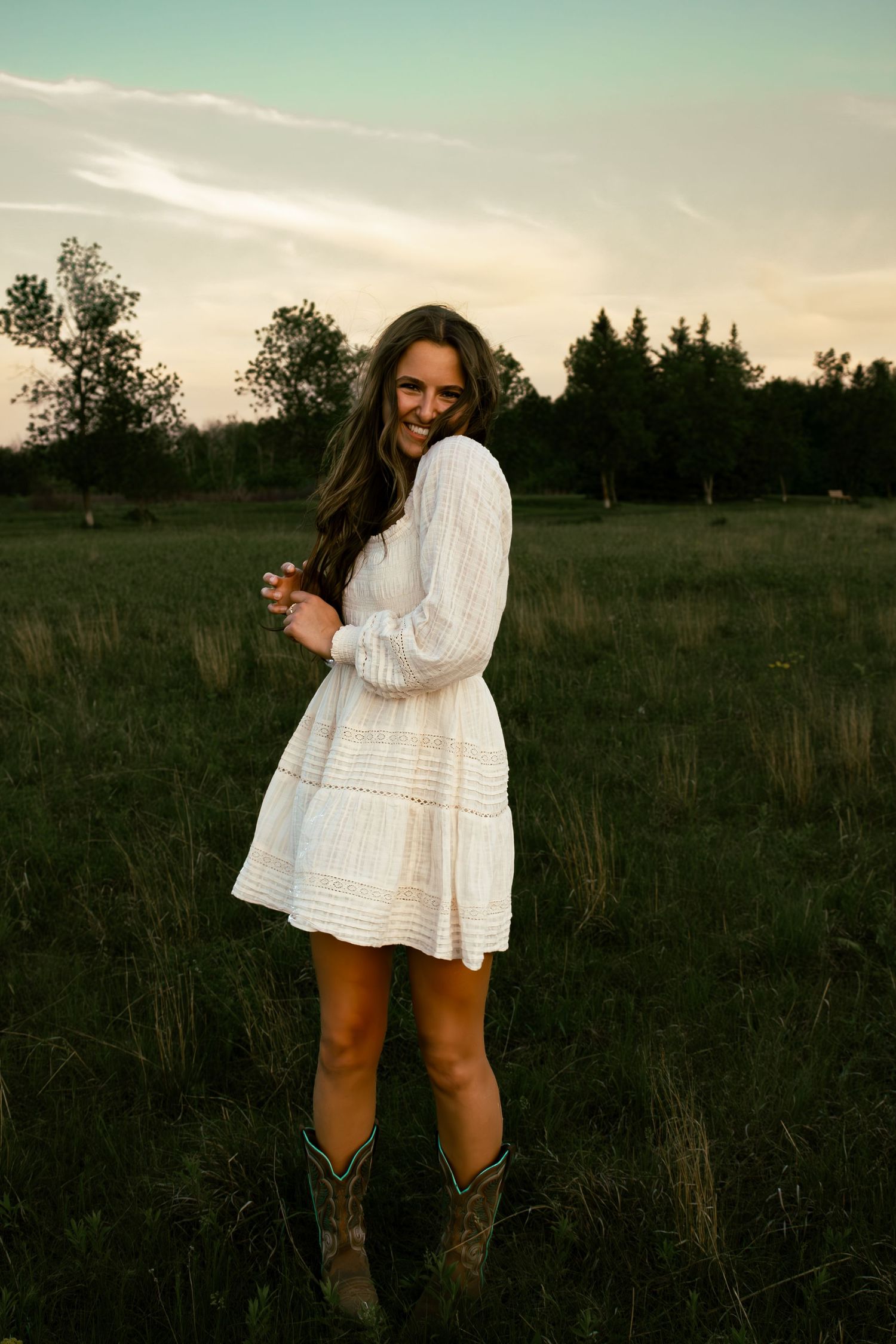 young woman posing in a field at sunset