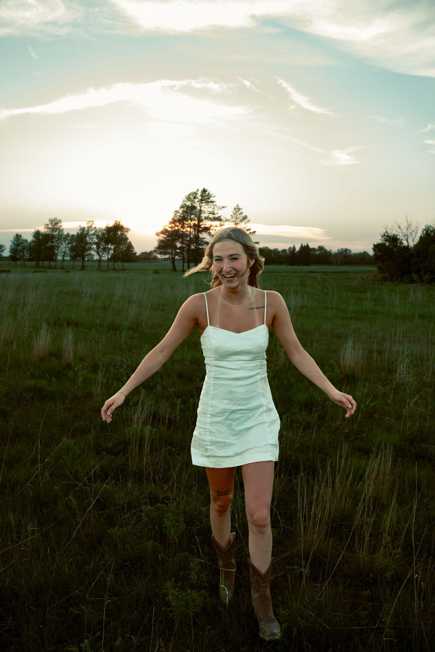 young woman posing in a field at sunset