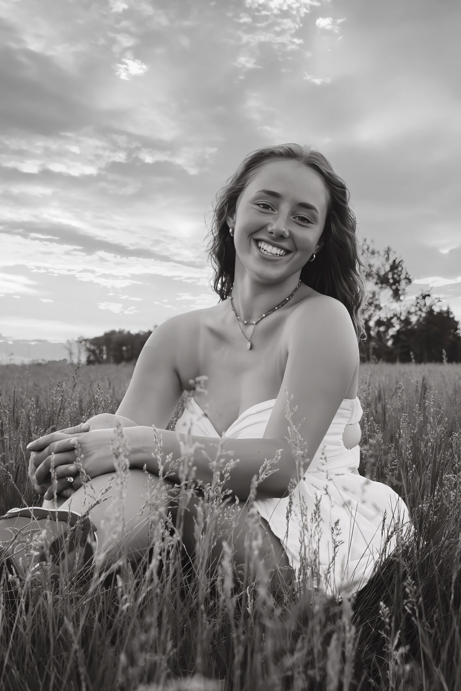 young woman posing in a field at sunset