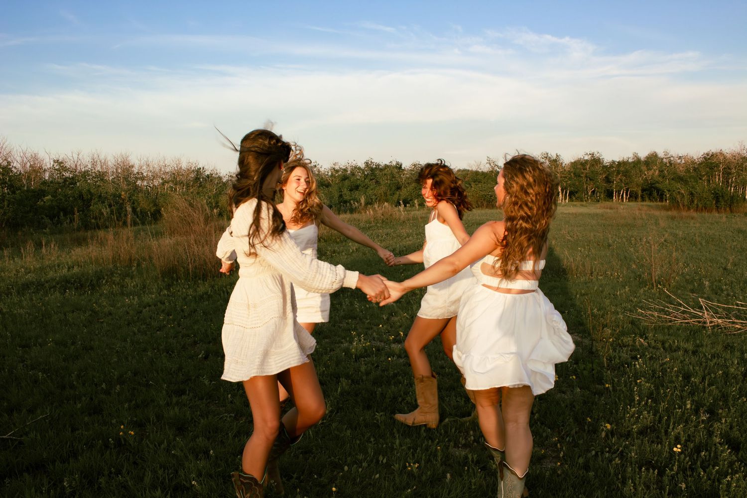 four female friends posing in a field at sunset