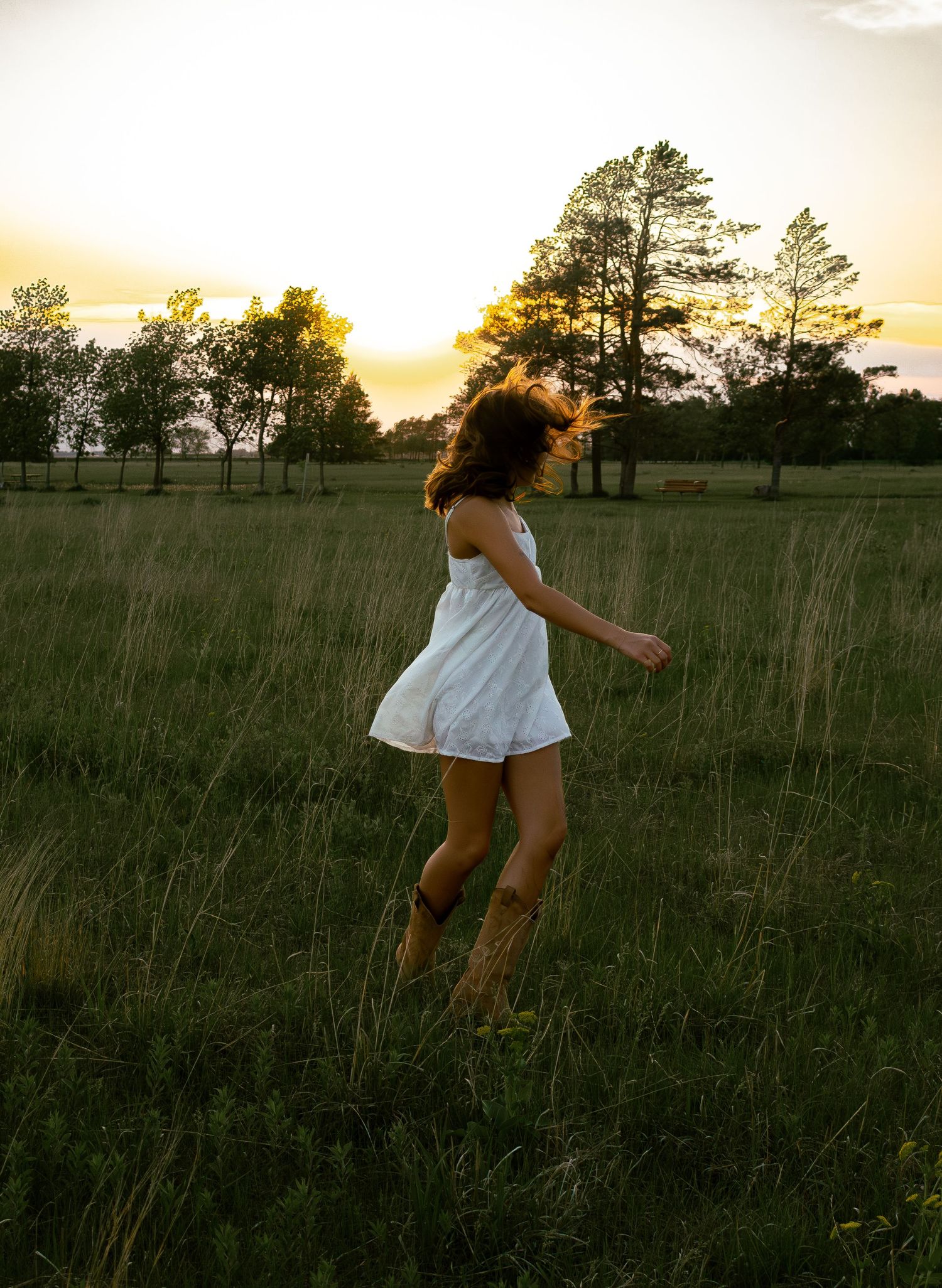young woman posing in a field at sunset