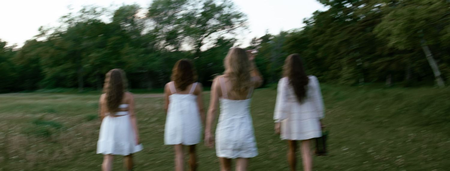 Group of four friends walking away towards a tree line