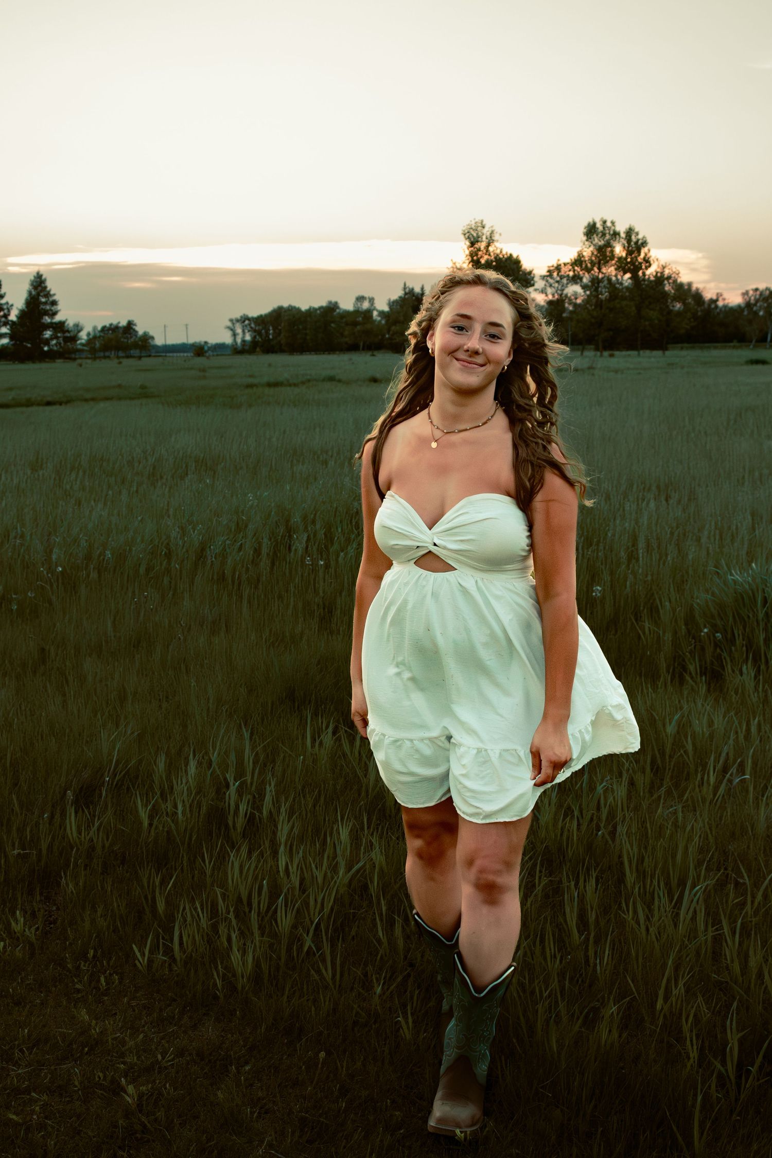 young woman posing in a field at sunset