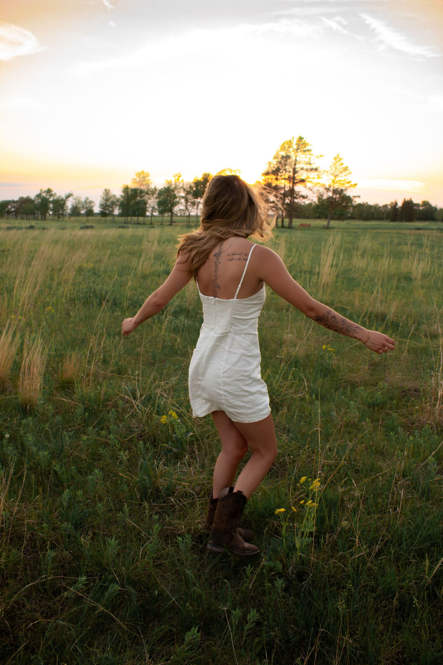 young woman posing in a field at sunset