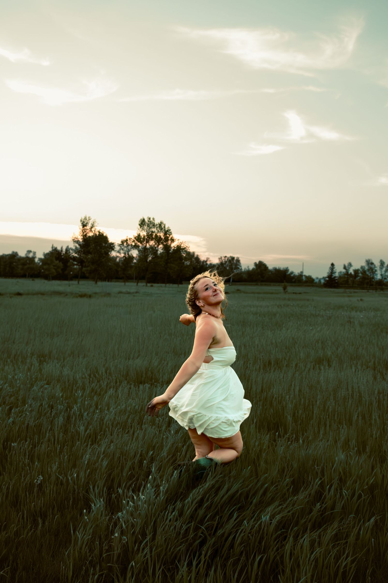 young woman posing in a field at sunset