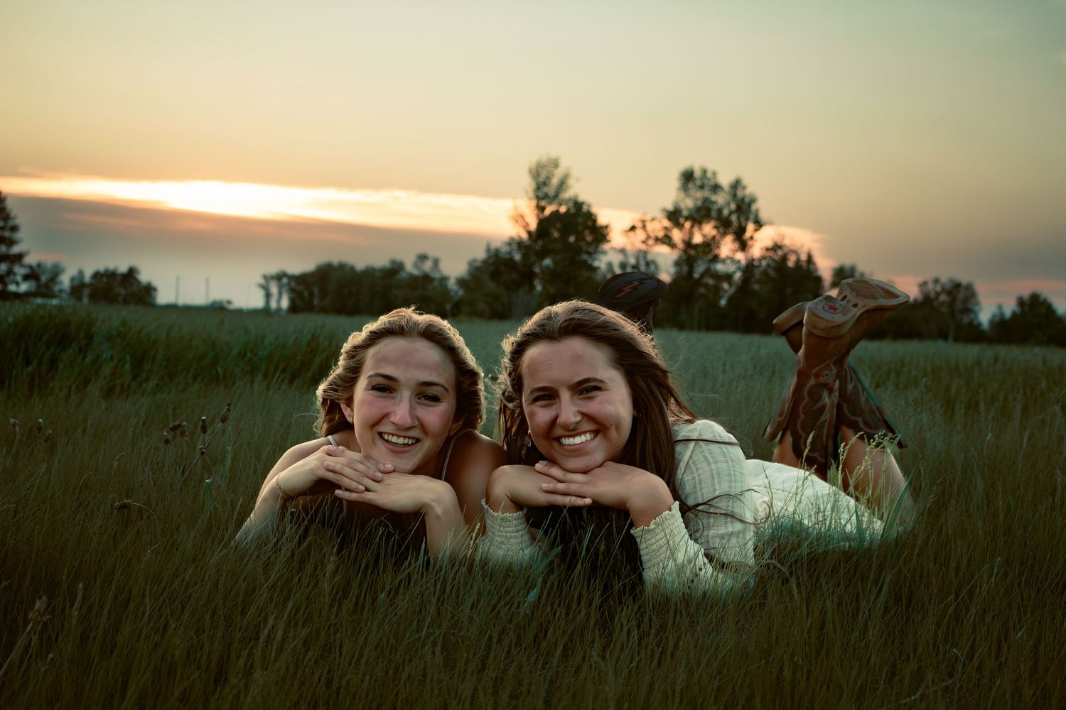 two female friends posing in a field at sunset
