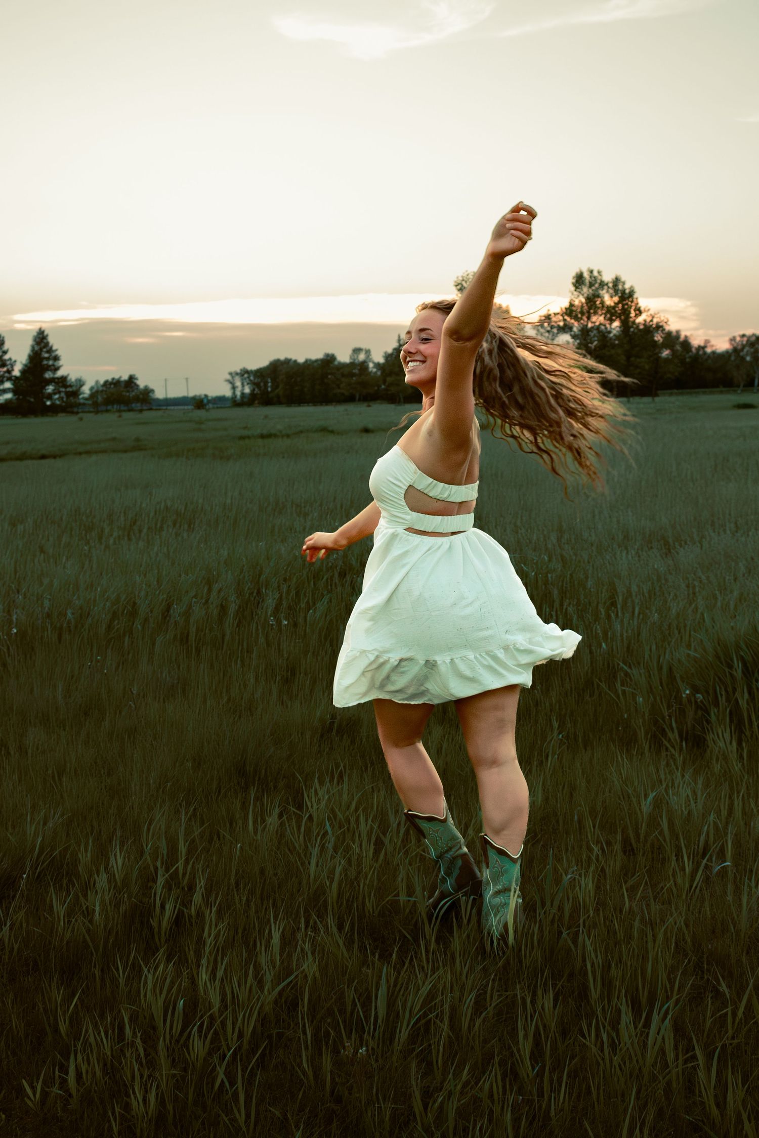 young woman posing in a field at sunset