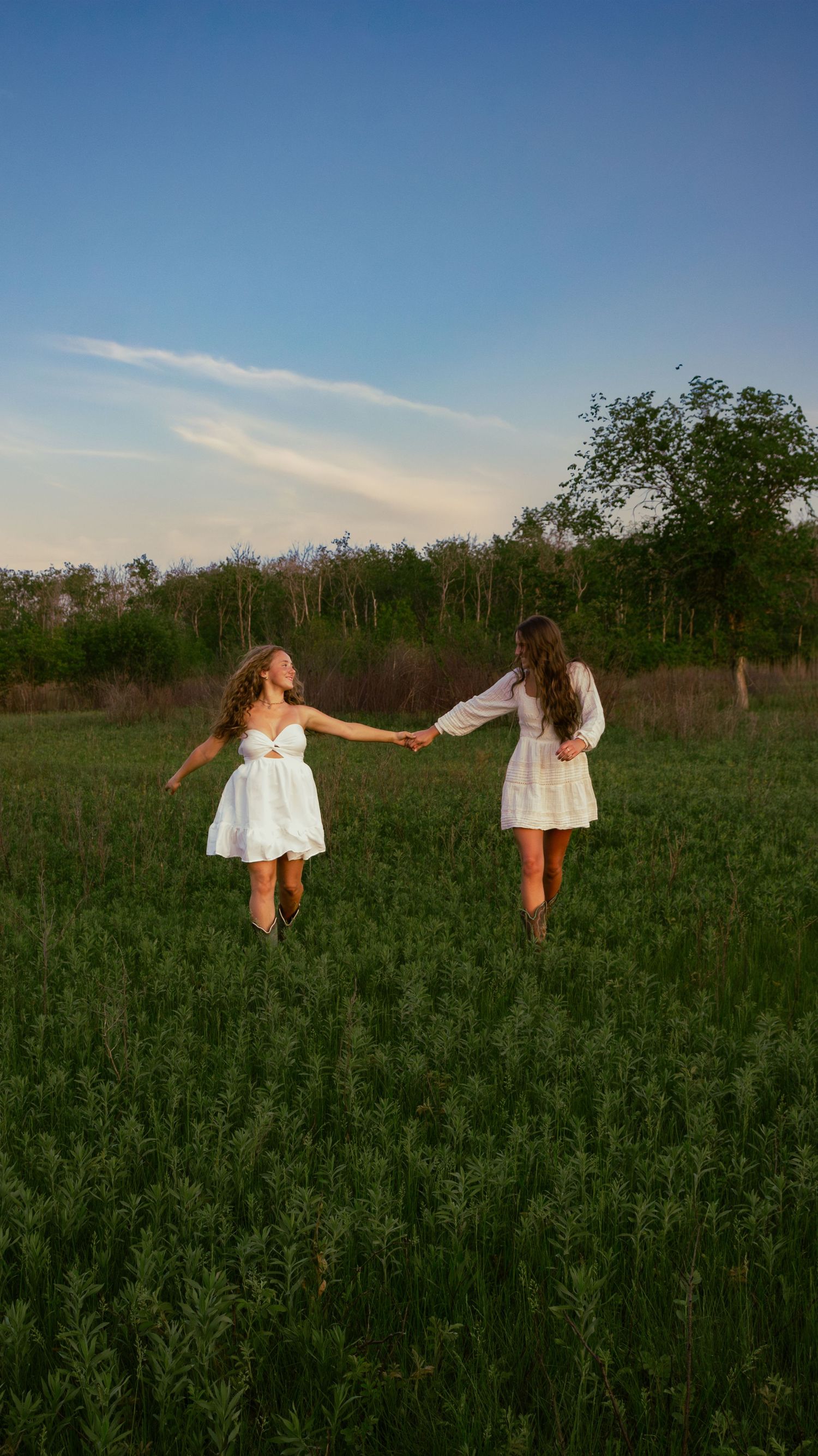 two female friends posing in a field at sunset