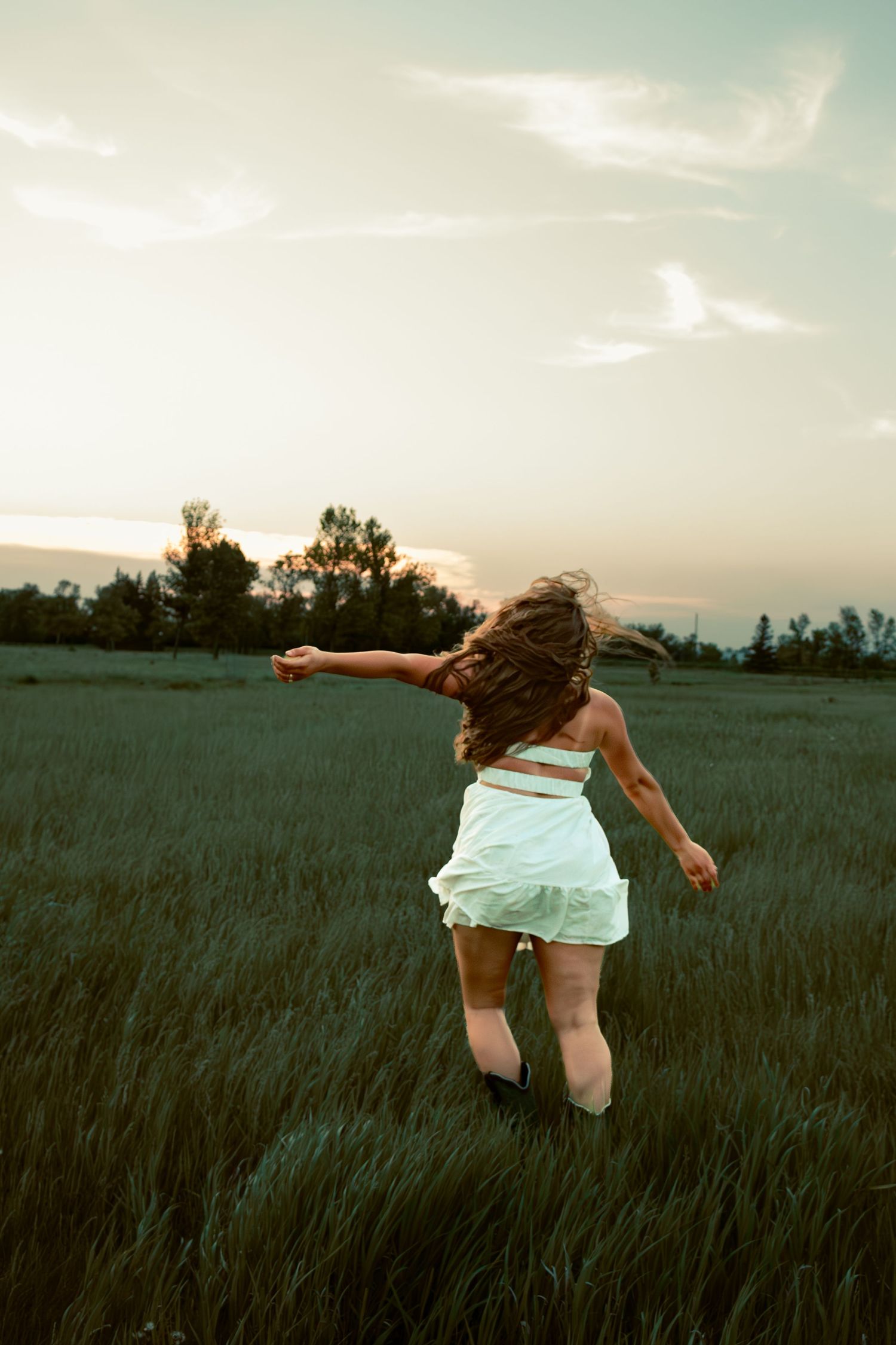 young woman posing in a field at sunset