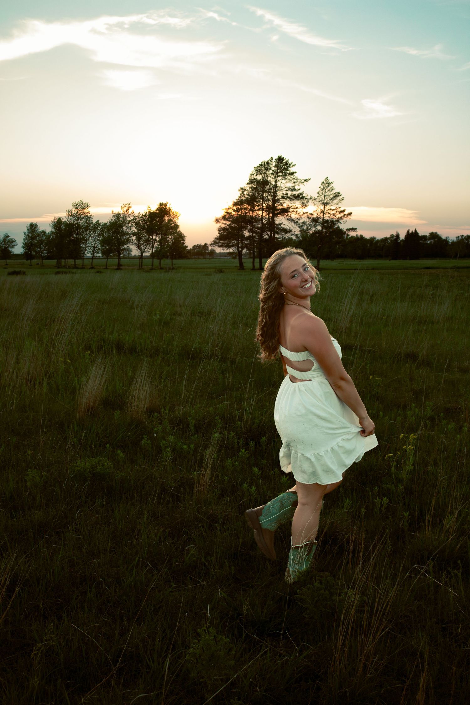 young woman posing in a field at sunset