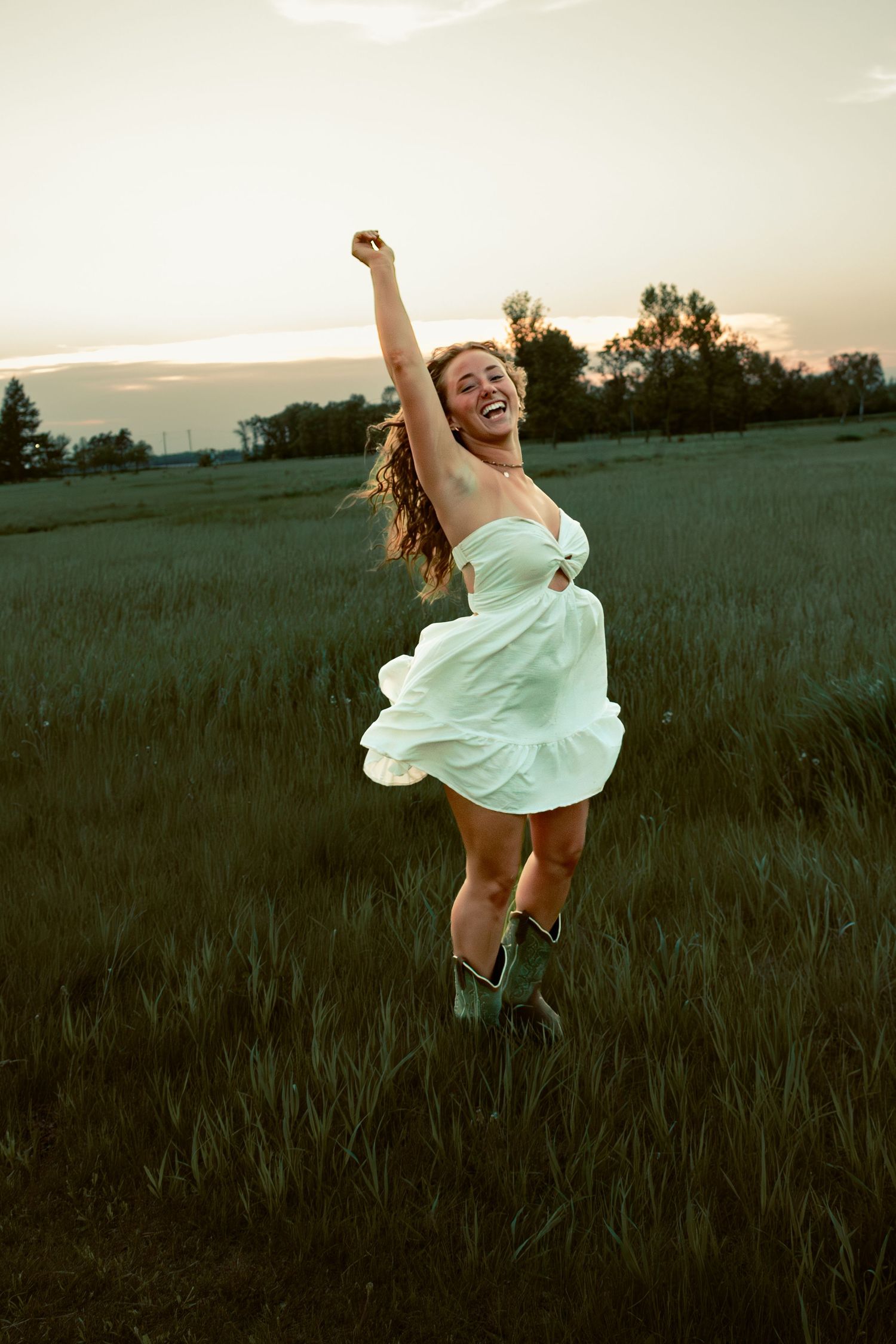 young woman posing in a field at sunset