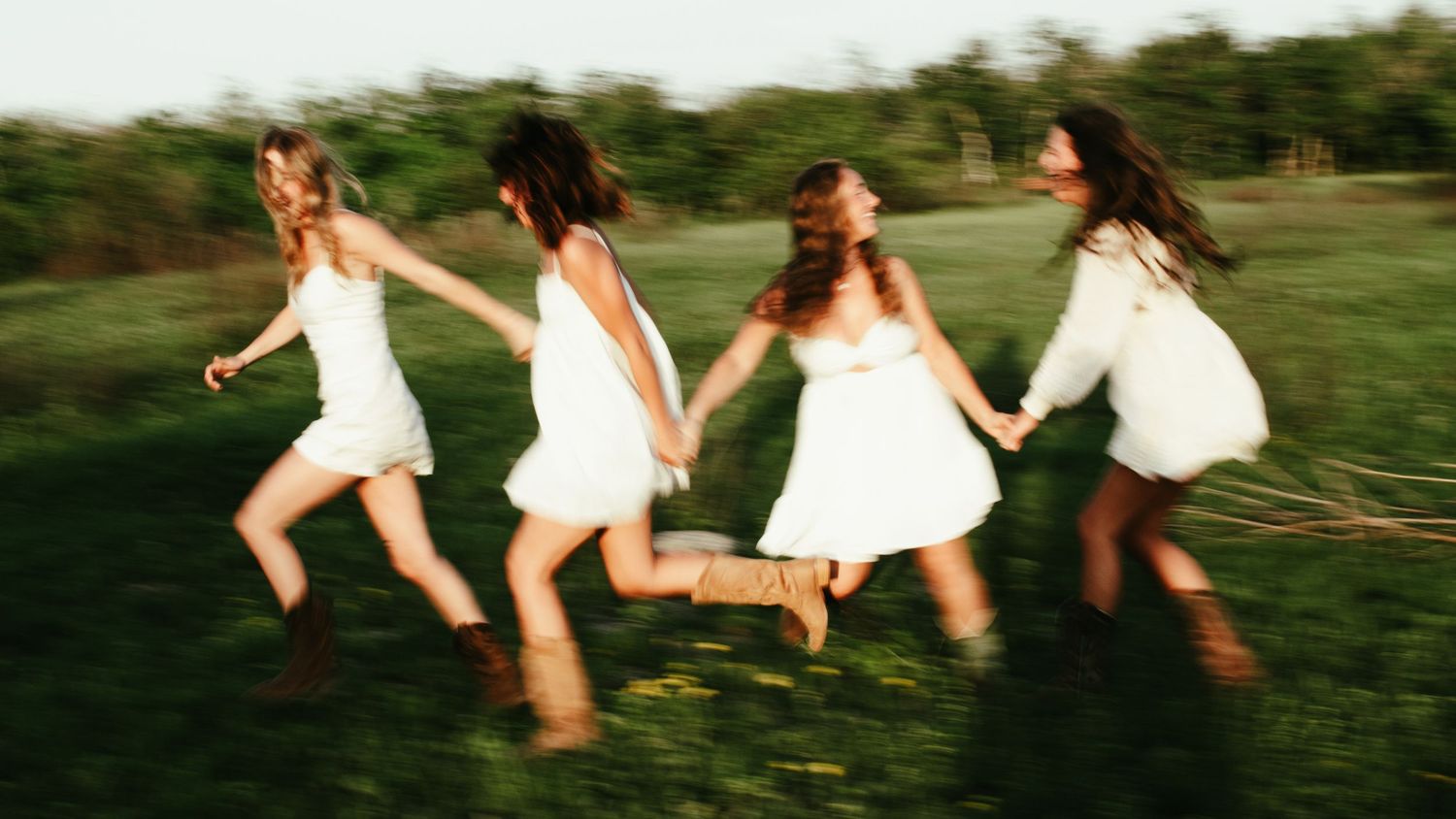 four female friends posing in a field at sunset