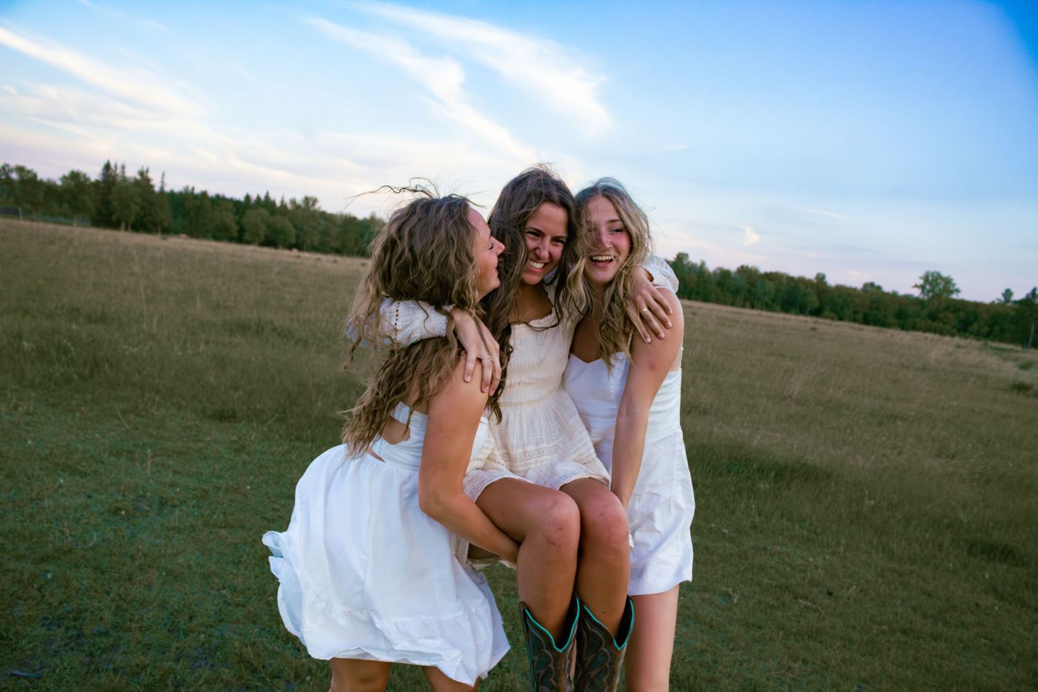 three young women two carrying the other one walking in a field