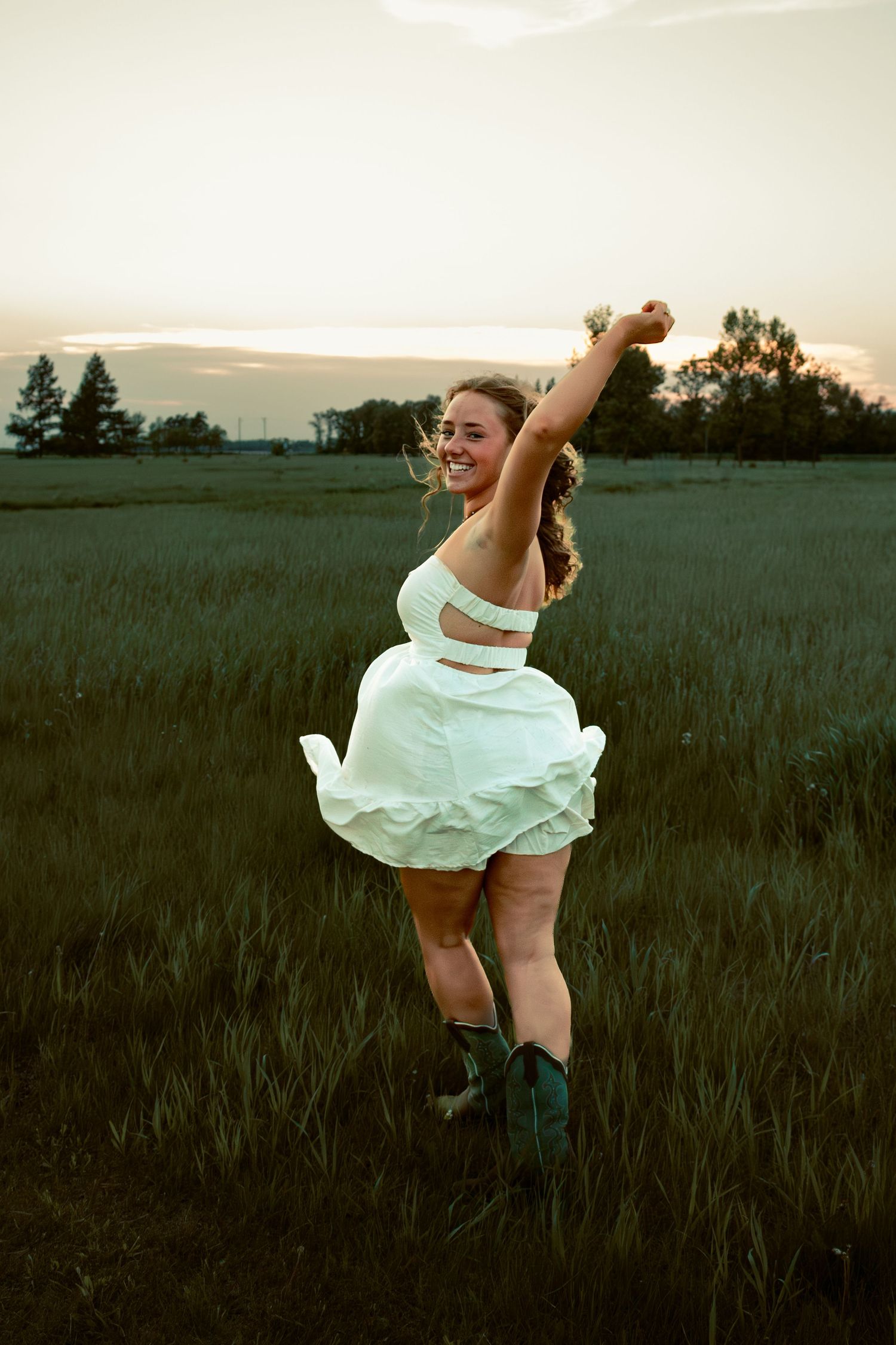 young woman posing in a field at sunset