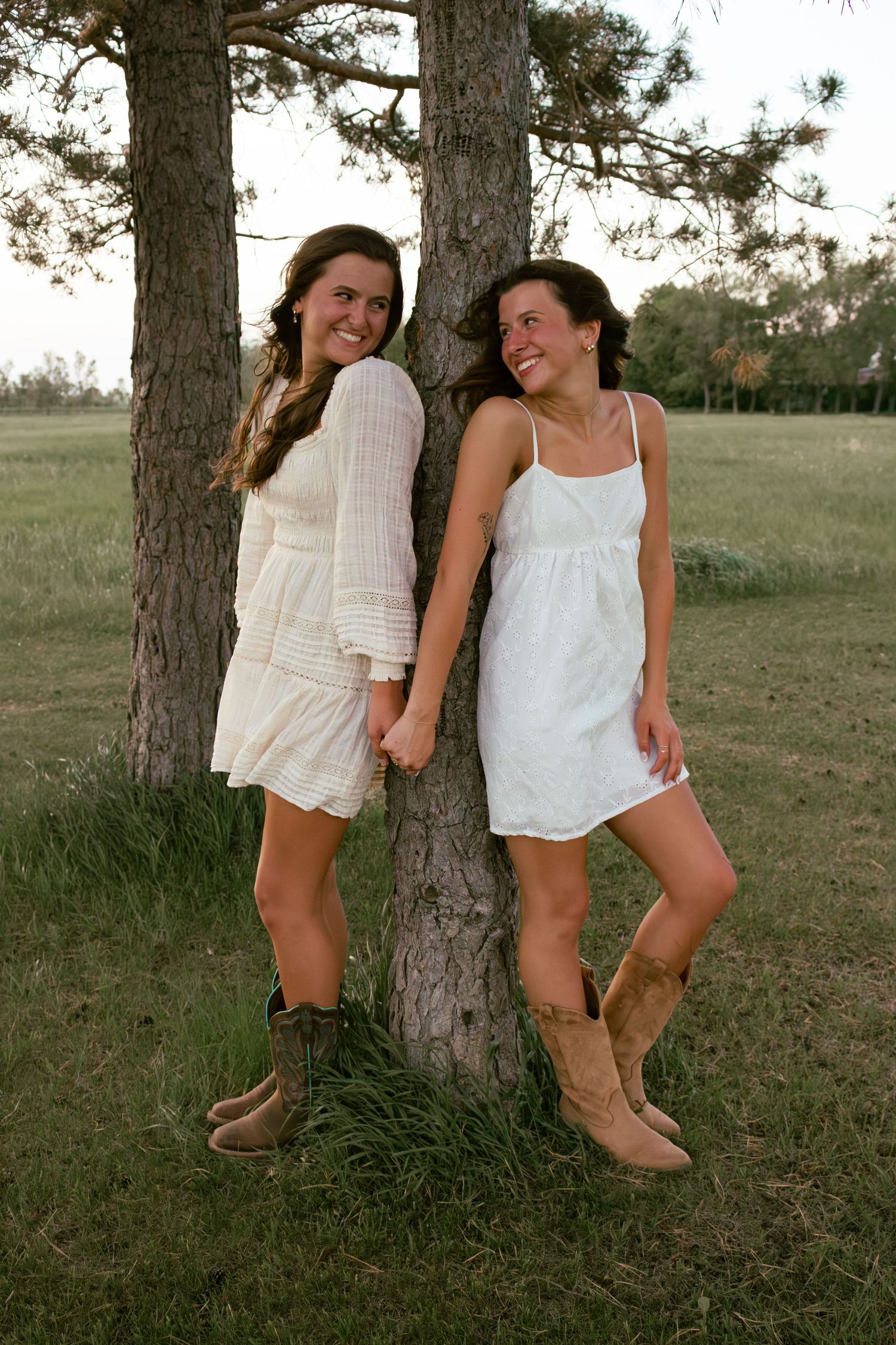 two female friends posing in a field at sunset
