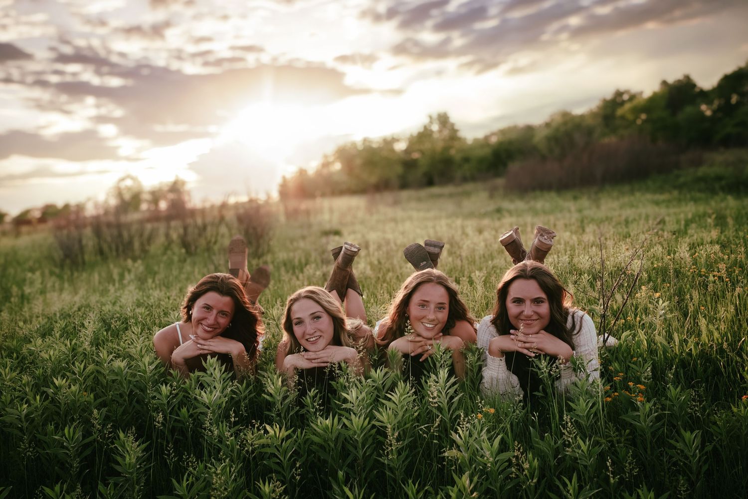 four female friends posing in a field at sunset