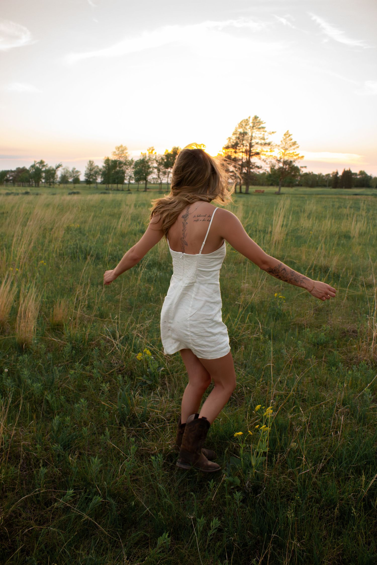 young woman posing in a field at sunset