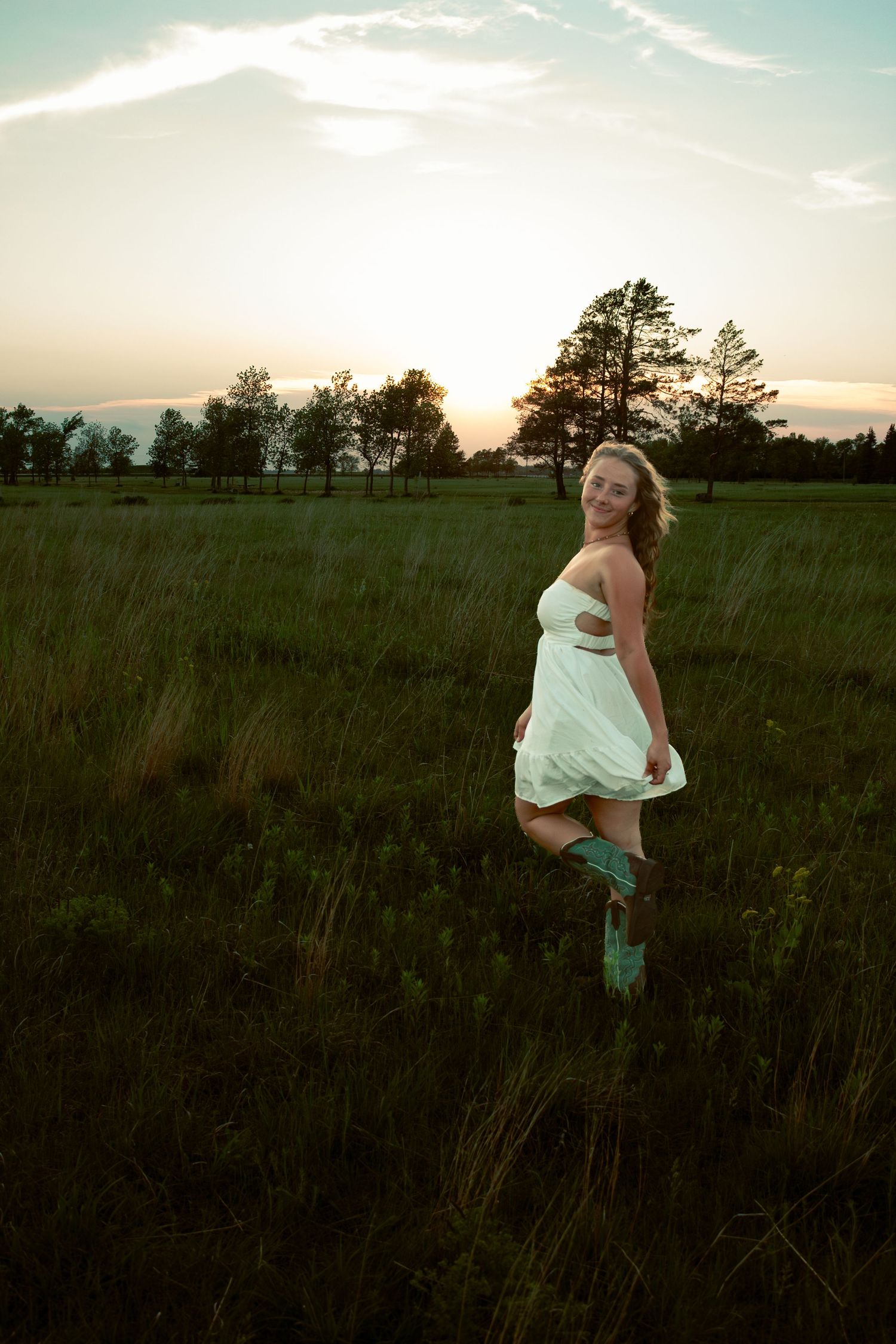 young woman posing in a field at sunset