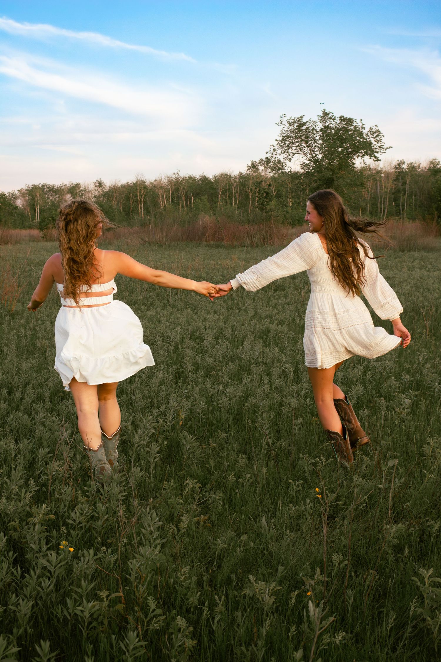 two female friends posing in a field at sunset
