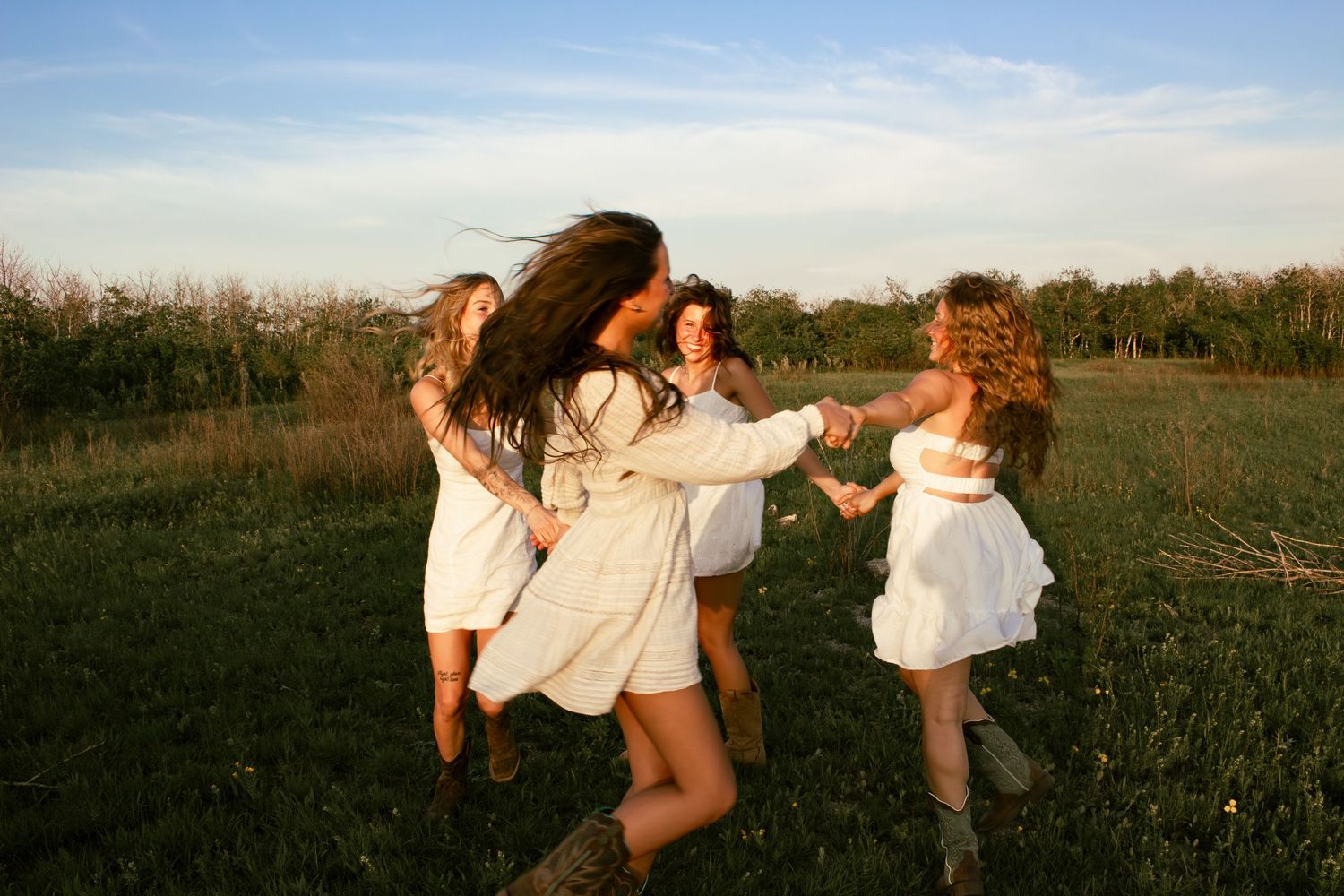 four female friends posing in a field at sunset