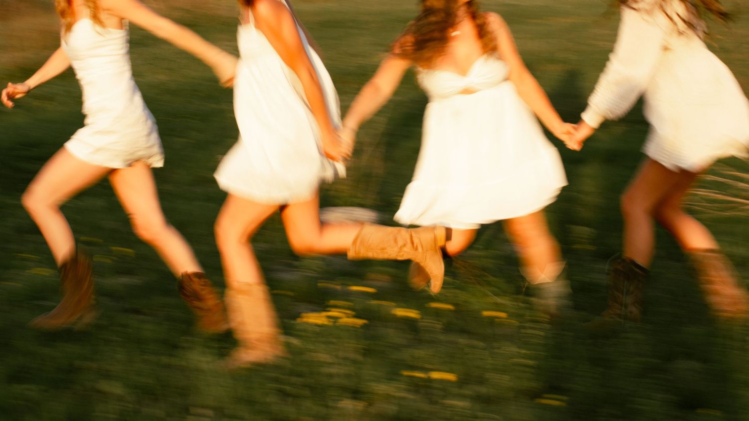 four female friends posing in a field at sunset