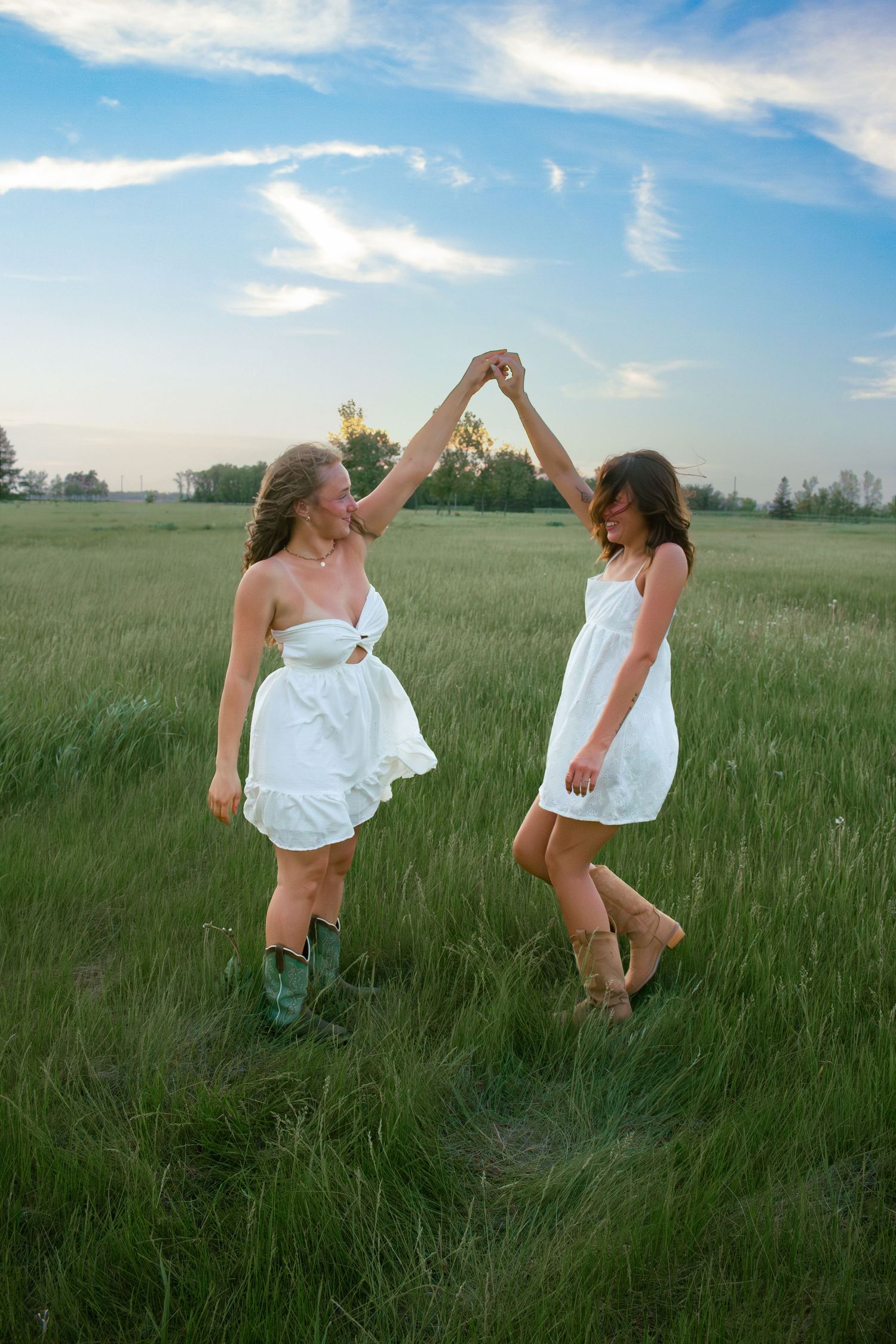two female friends posing in a field at sunset