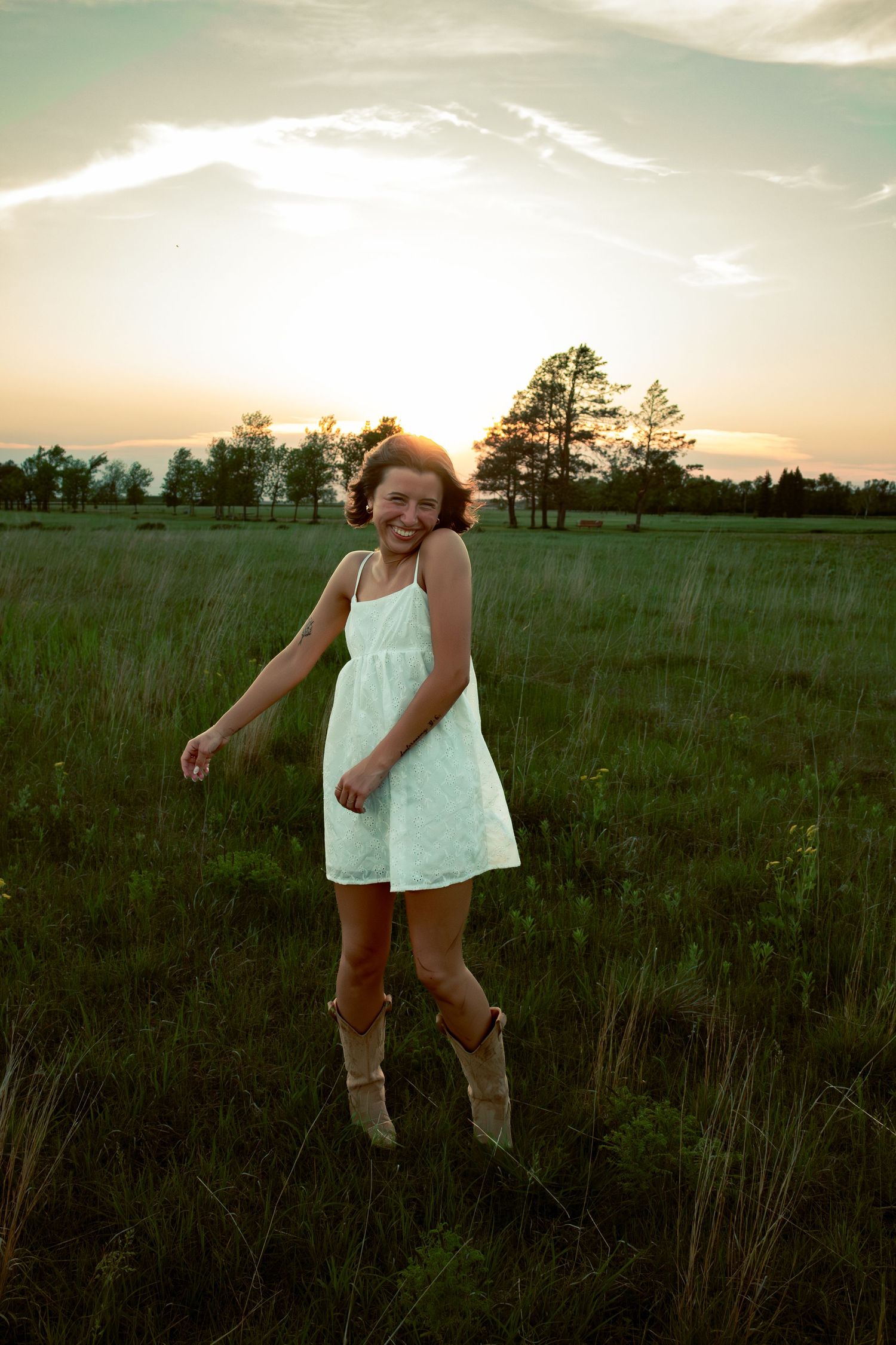 young woman posing in a field at sunset