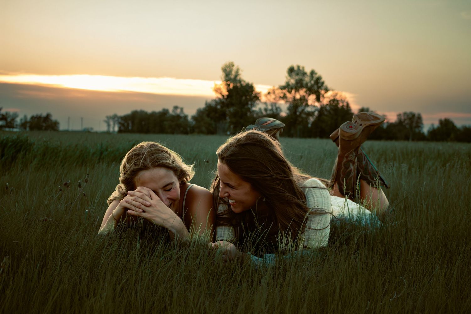 two female friends posing in a field at sunset