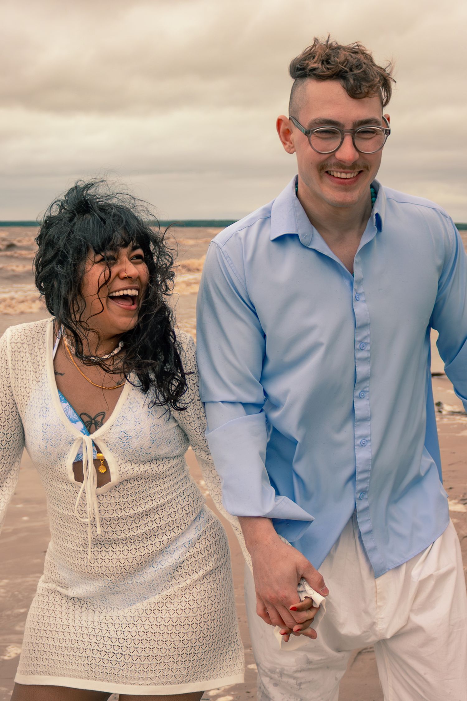 couple holding hands and laughing at the beach