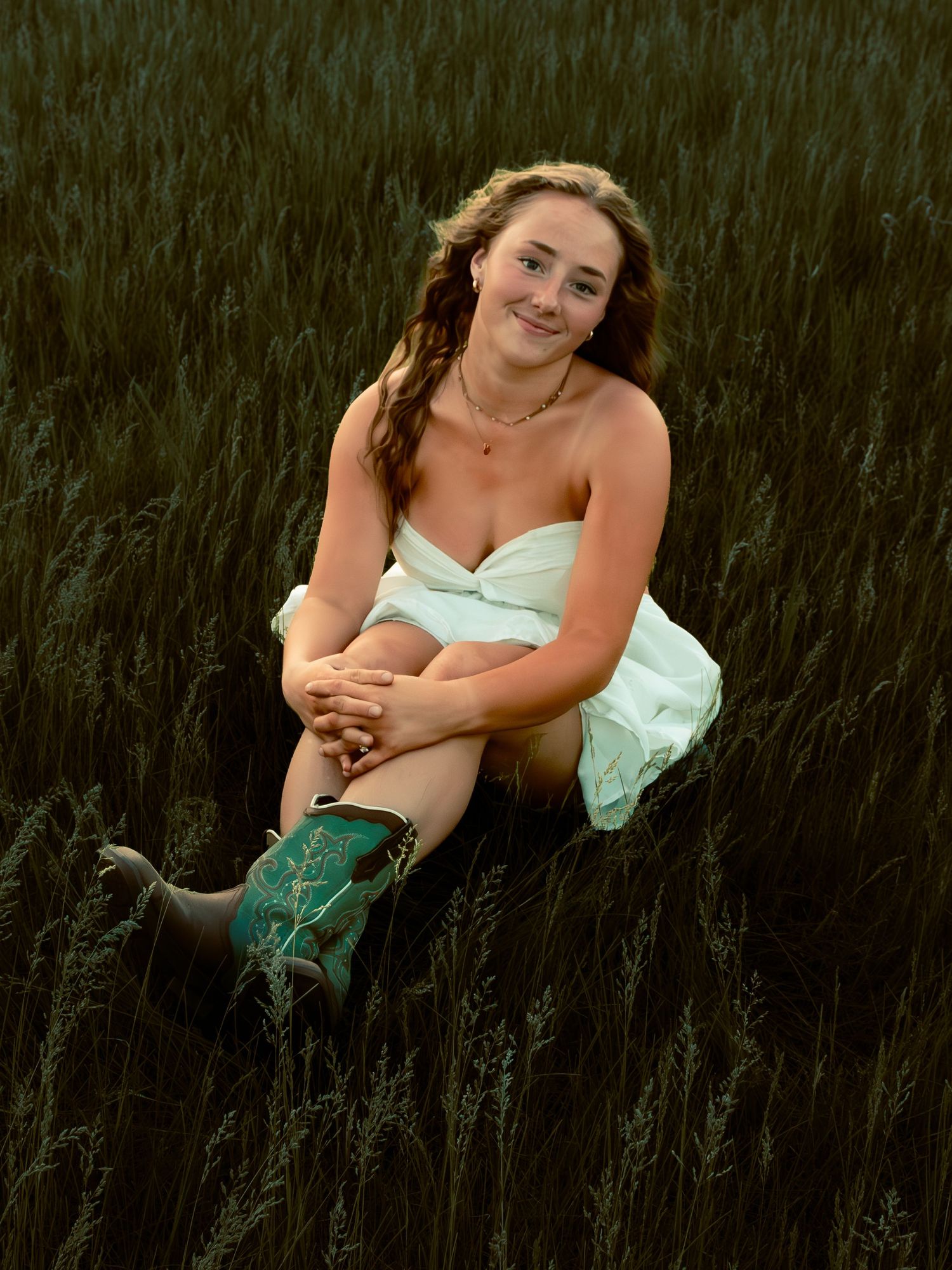 young woman posing in a field at sunset