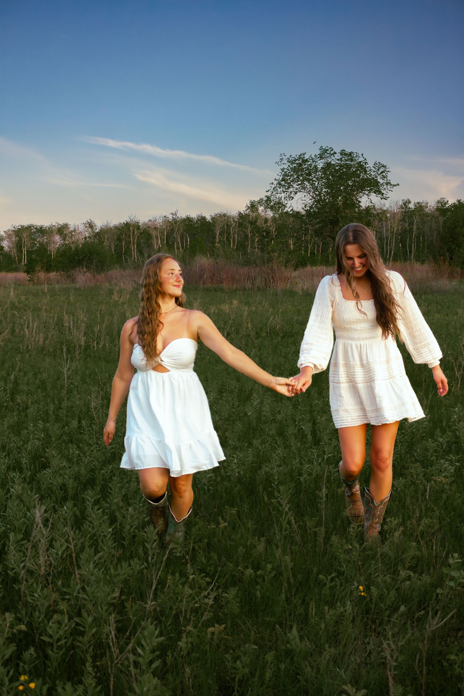 two female friends posing in a field at sunset