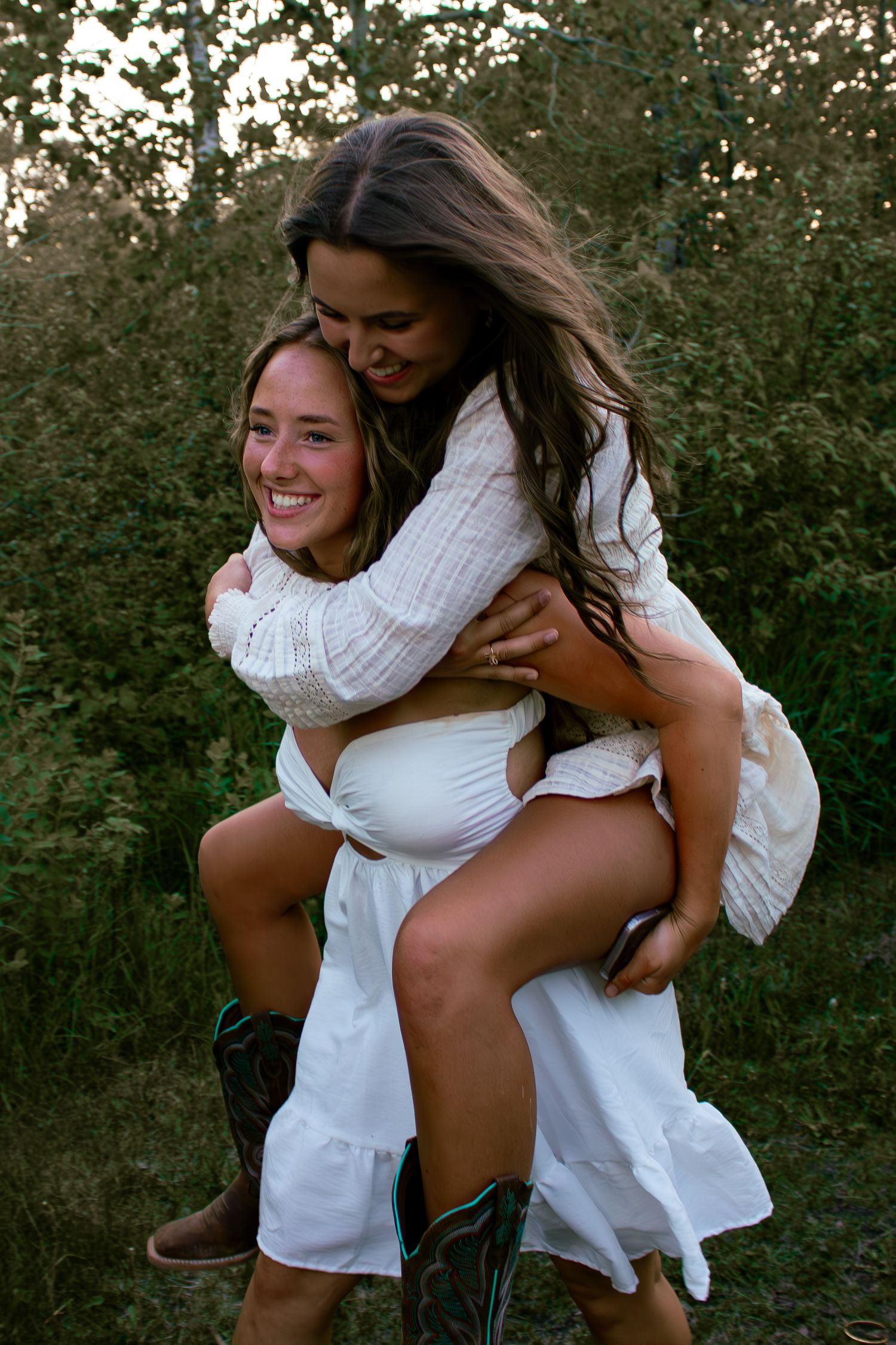two female friends posing in a field at sunset