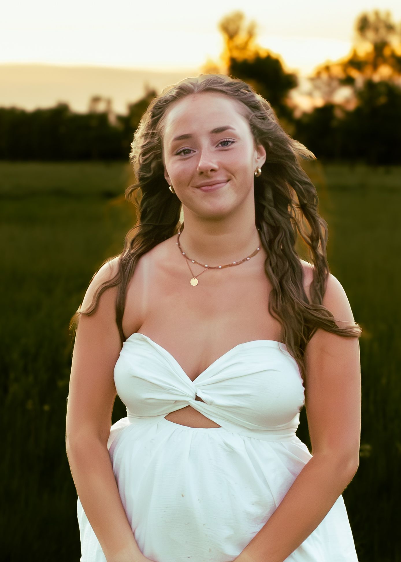 young woman posing in a field at sunset