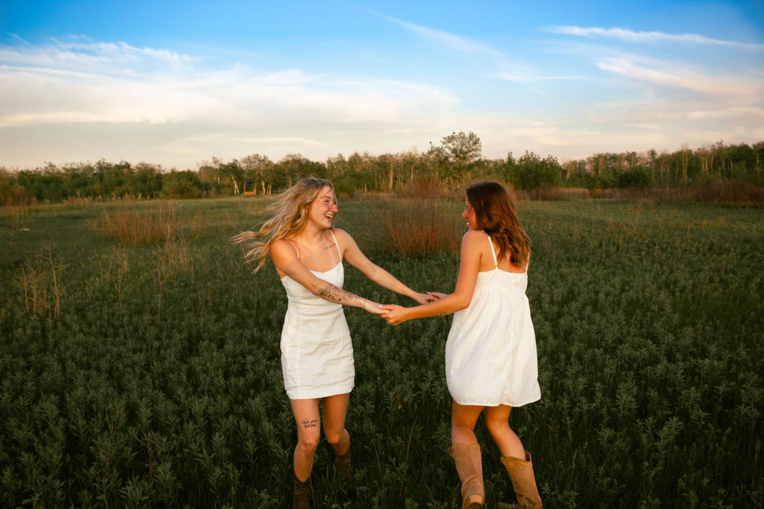 two female friends spinning around each other in a field