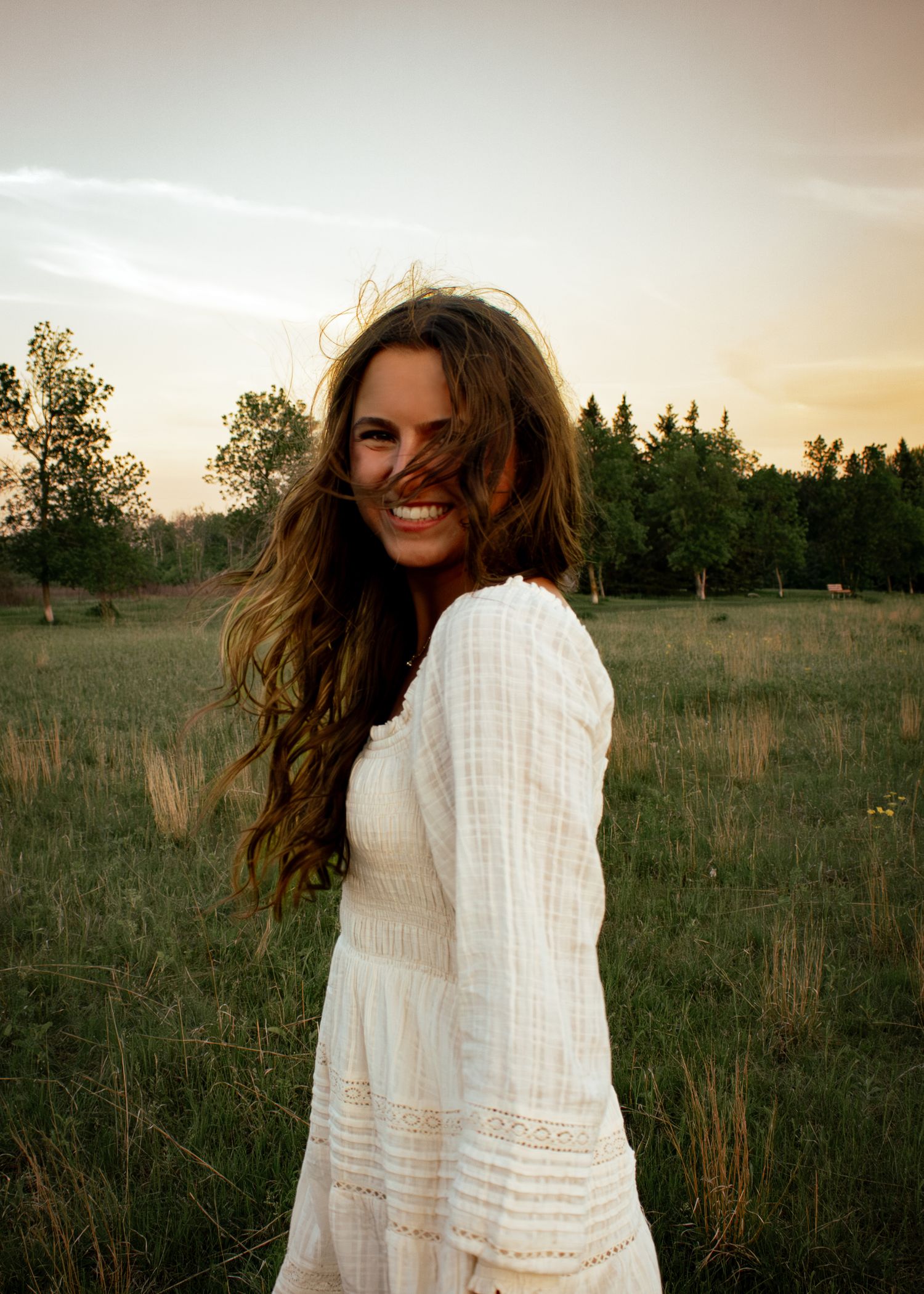 young woman posing in a field at sunset