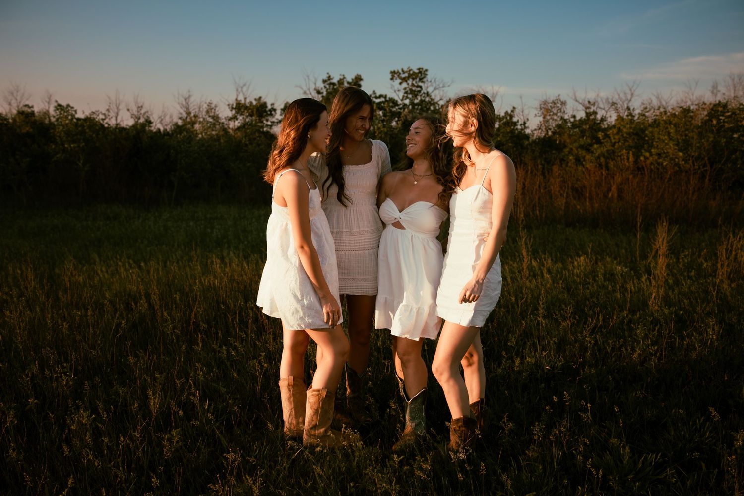 four female friends posing in a field at sunset