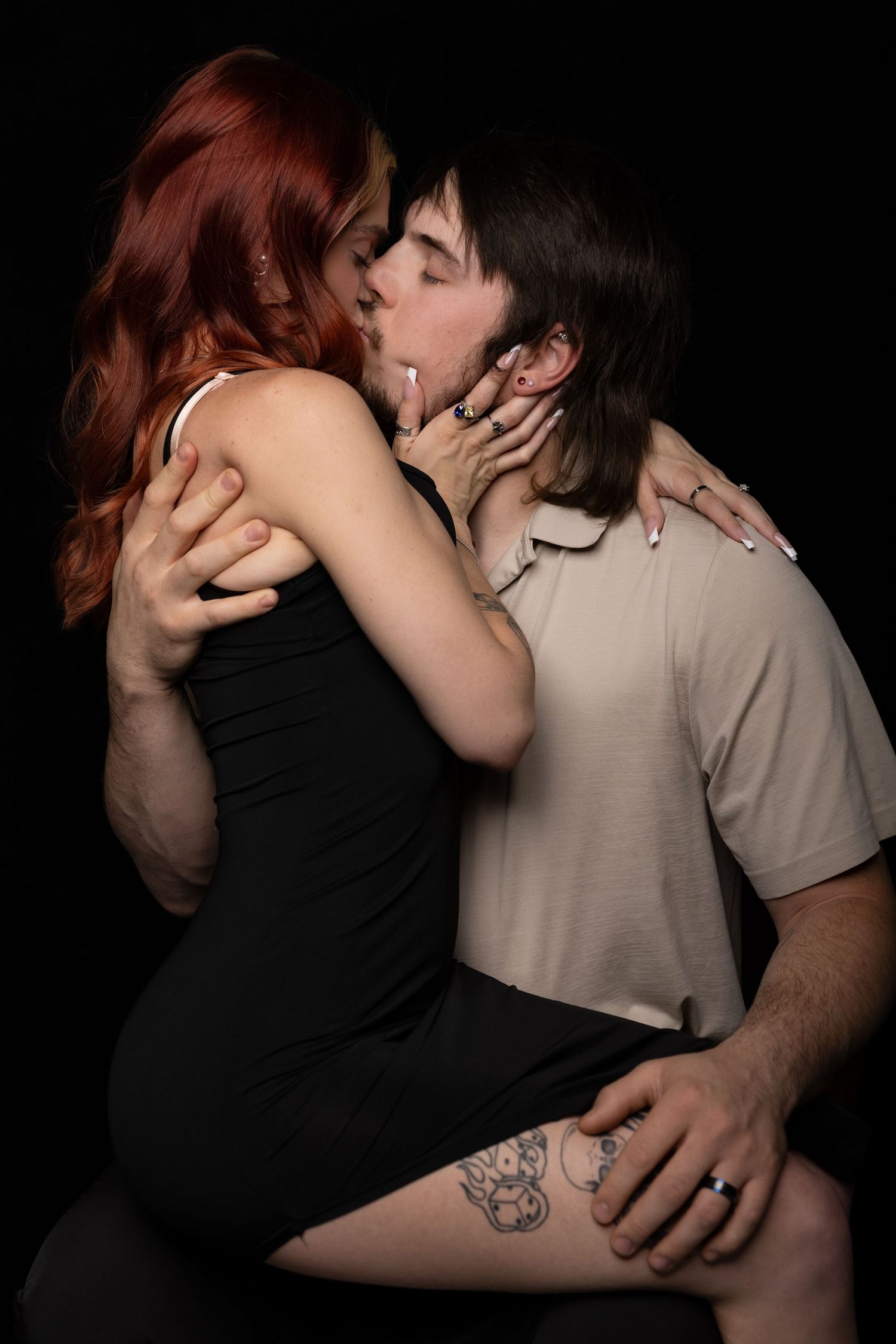 A passionate young couple embrace with a  kiss against a dark studio background.
