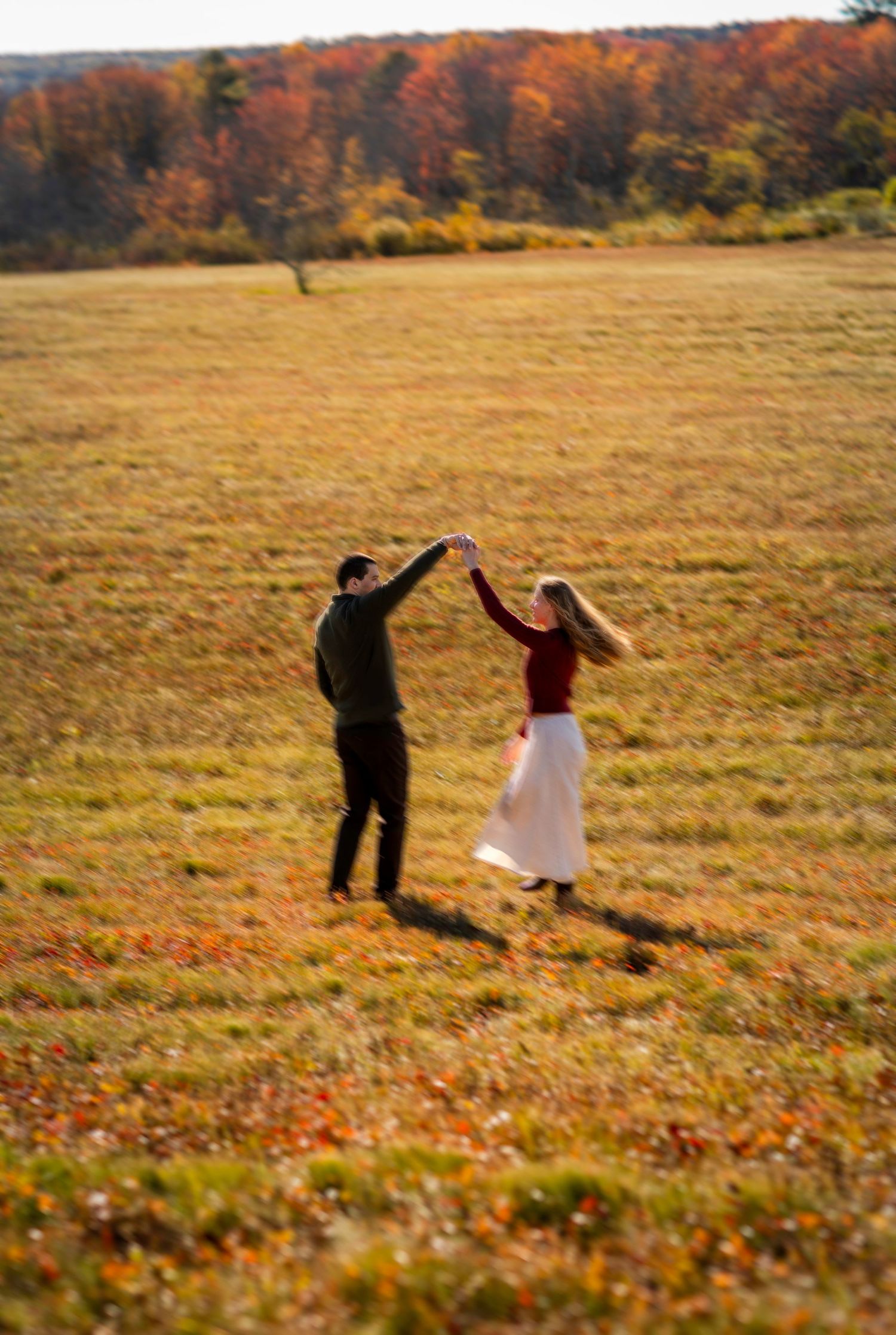 Couple twirling in the a field in the fall
