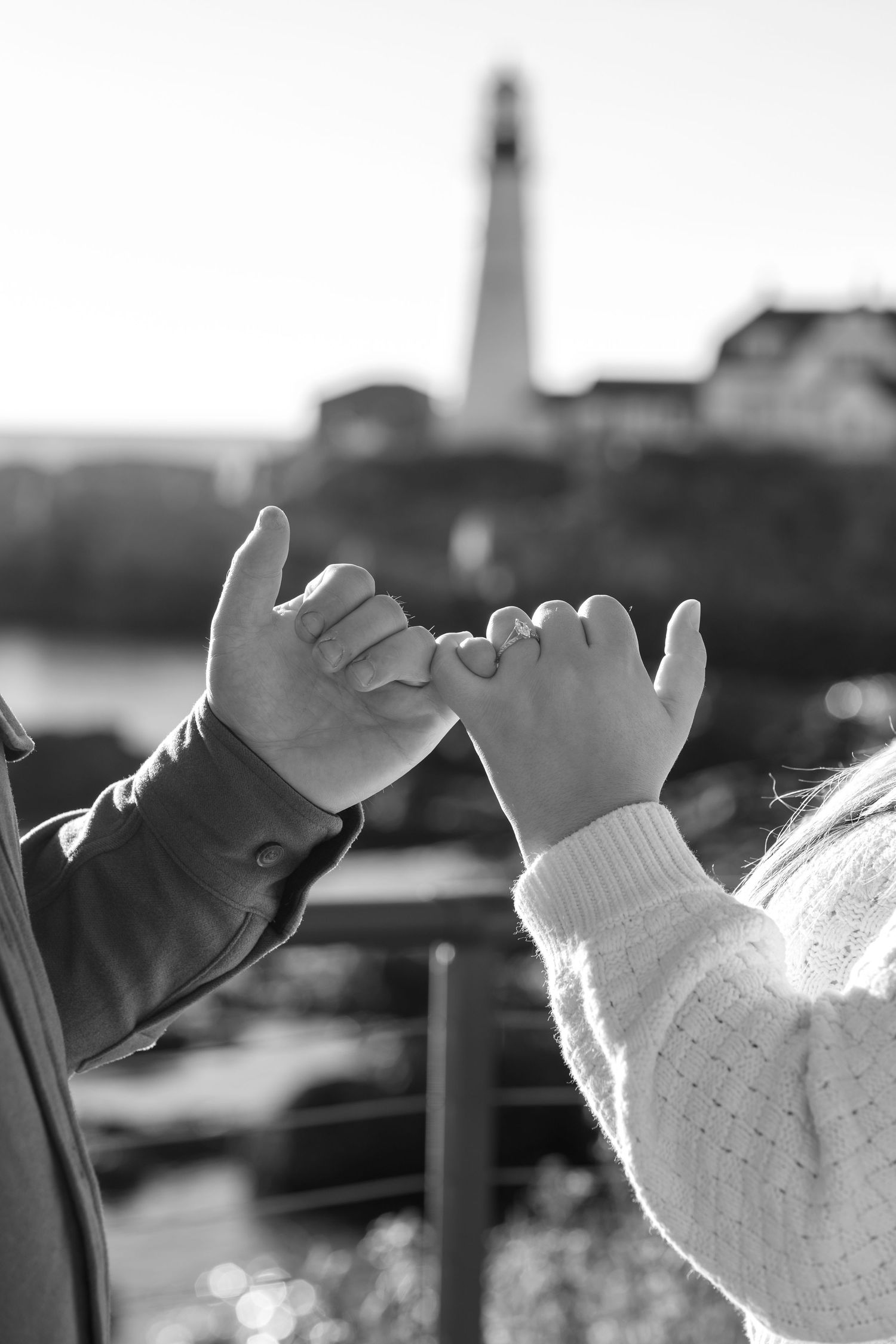 Black and white photo of a pinky promise with an engagement ring